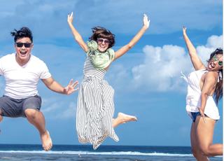 three laughing friends captured in a mid air jump at the Alameda waterfront