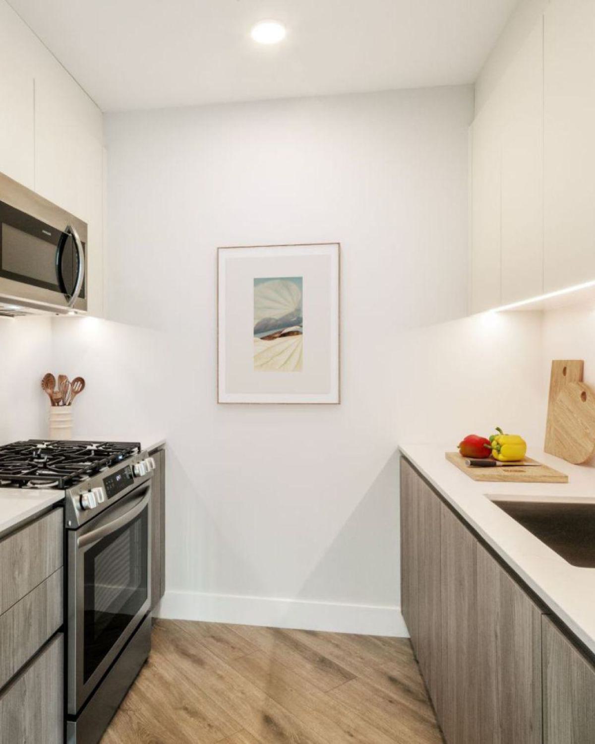 modern kitchen with a Grey Nordic Palette, featuring light wood cabinetry, white upper cabinets, stainless steel appliances, and a marble backsplas