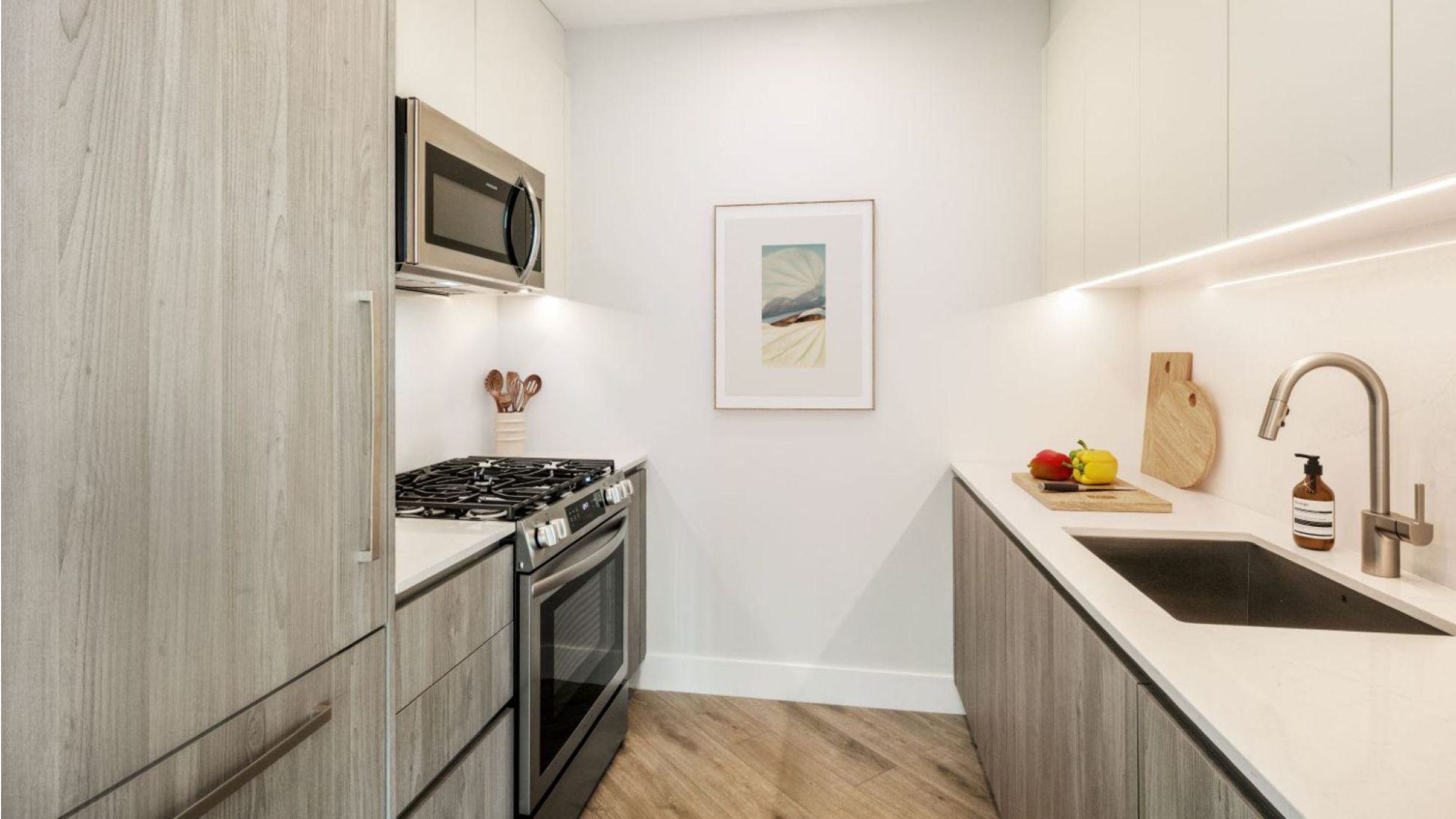 modern kitchen with a Grey Nordic Palette, featuring light wood cabinetry, white upper cabinets, stainless steel appliances, and a marble backsplas