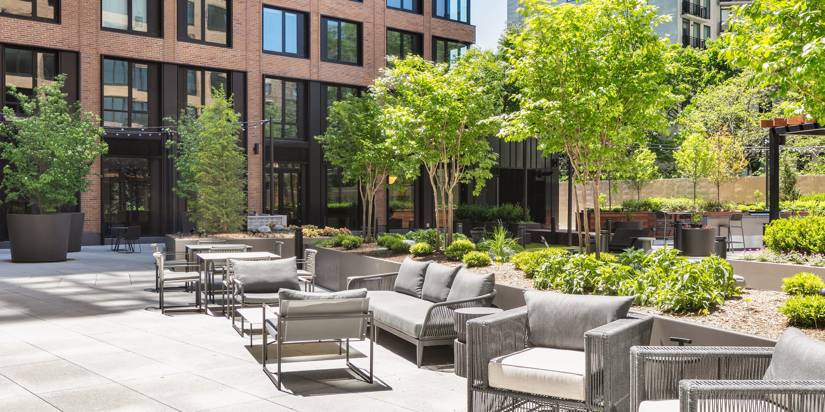 aerial view of a loden residential complex featuring two high-rise towers surrounding a landscaped courtyard with walking paths, greenery, and seating areas
