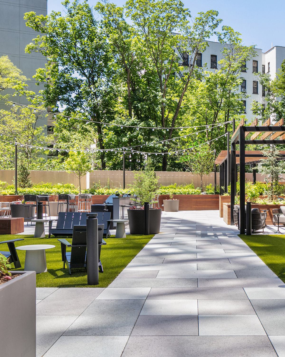 outdoor lounge featuring a central fire pit, plush seating, and a blooming cherry blossom tree, creating a cozy and elegant gathering space.