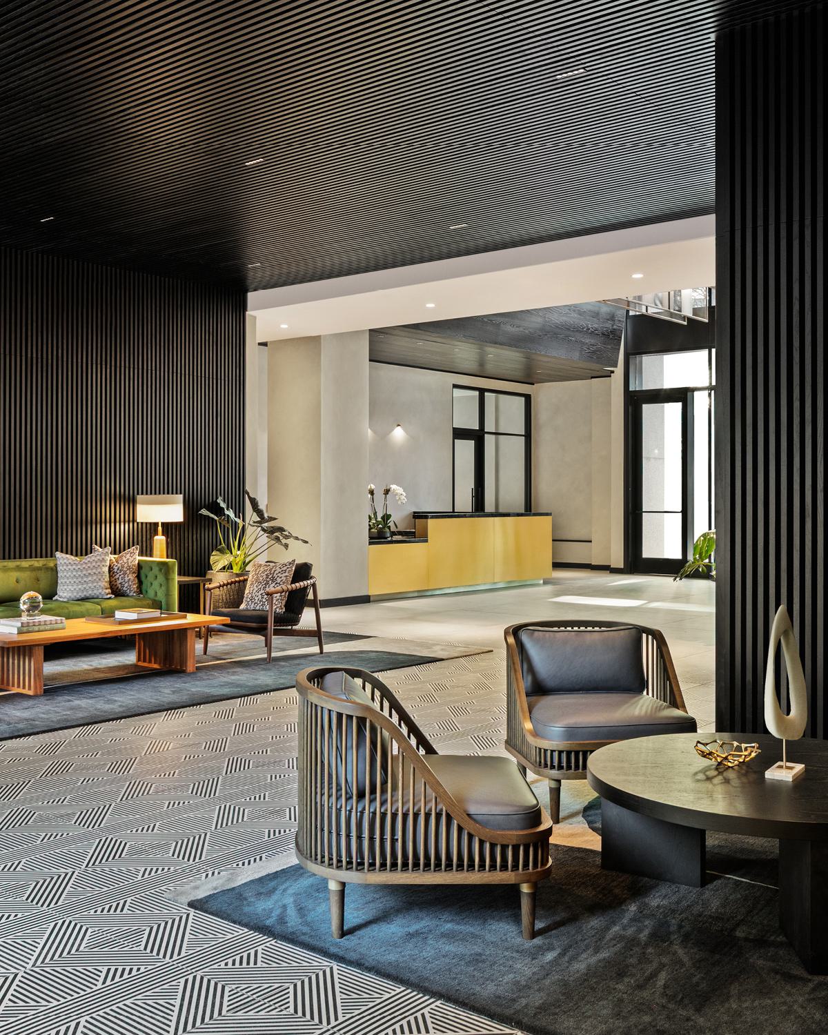 sophisticated lobby featuring a sleek gold reception desk, dark wood ceiling accents, and a seamless transition to a lush courtyard lounge.
