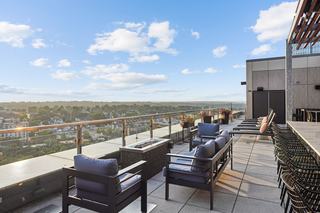 outdoor rooftop skydeck terrace lounge at vela with transparent glass balcony, sweeping views,  chaise lounge chairs, lots of comfy seating, and more.