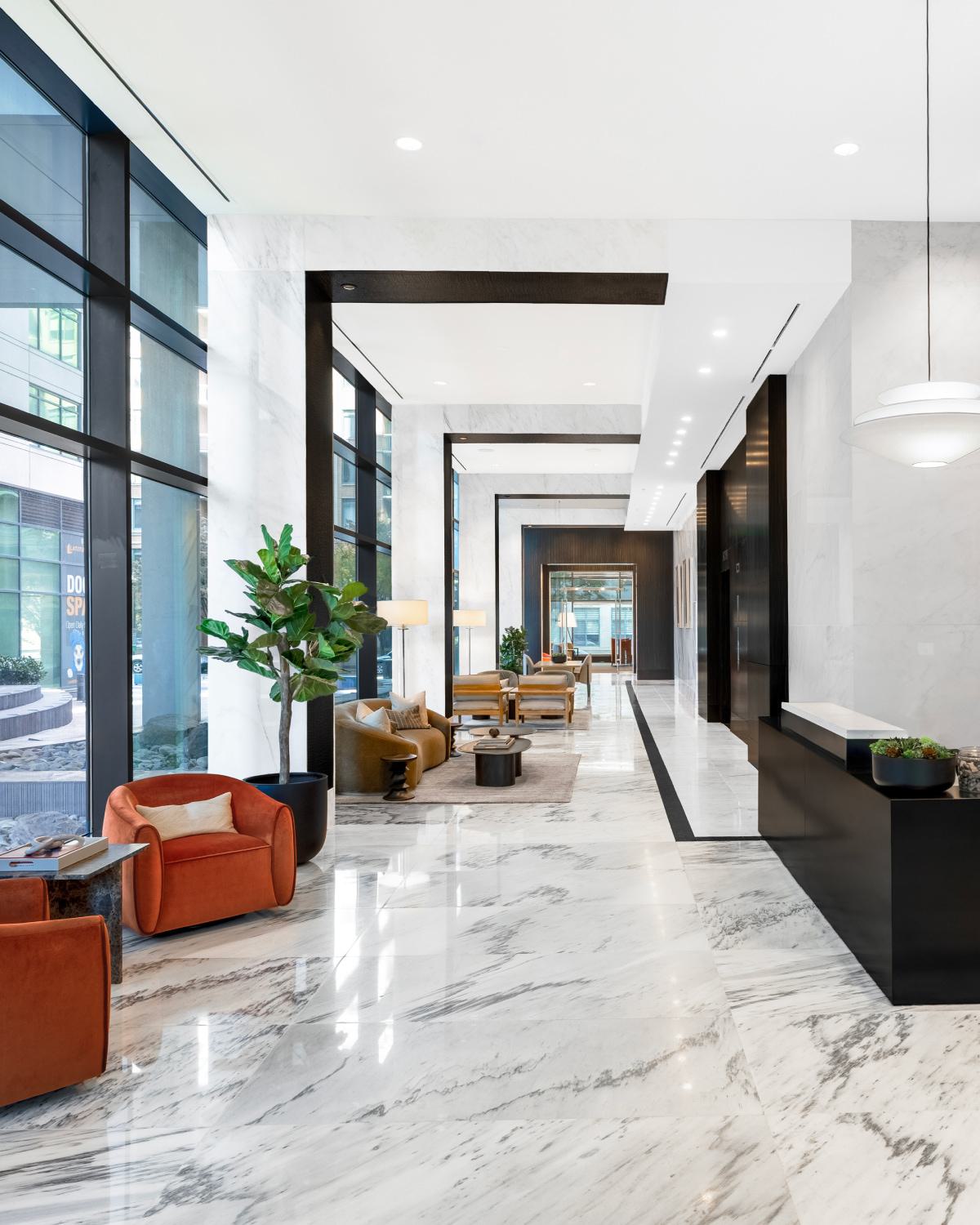 Sunlit lobby at Latitude Apartments in Virginia Square featuring modern lounge seating, marble floors, floor-to-ceiling windows, and a refined contemporary design.