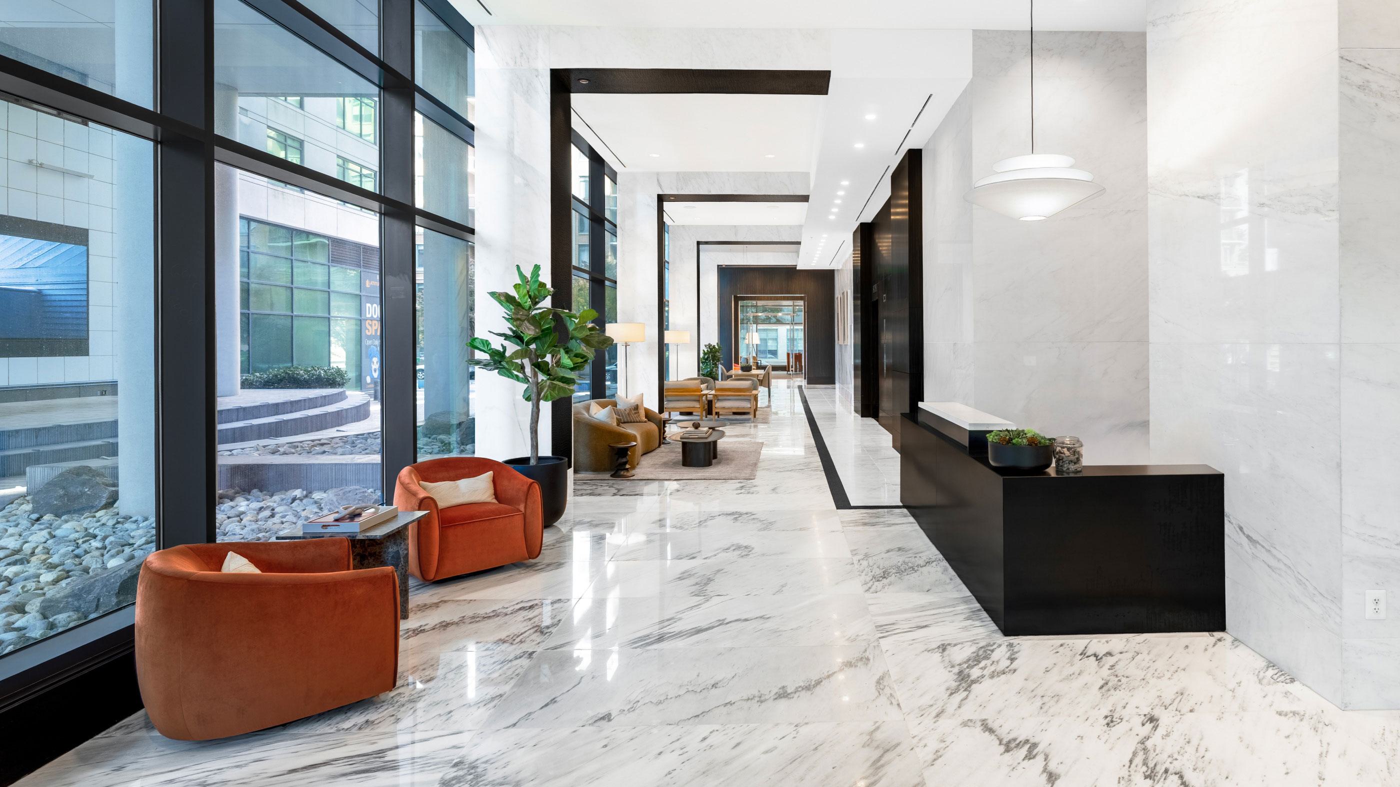 Sunlit lobby at Latitude Apartments in Virginia Square featuring modern lounge seating, marble floors, floor-to-ceiling windows, and a refined contemporary design.