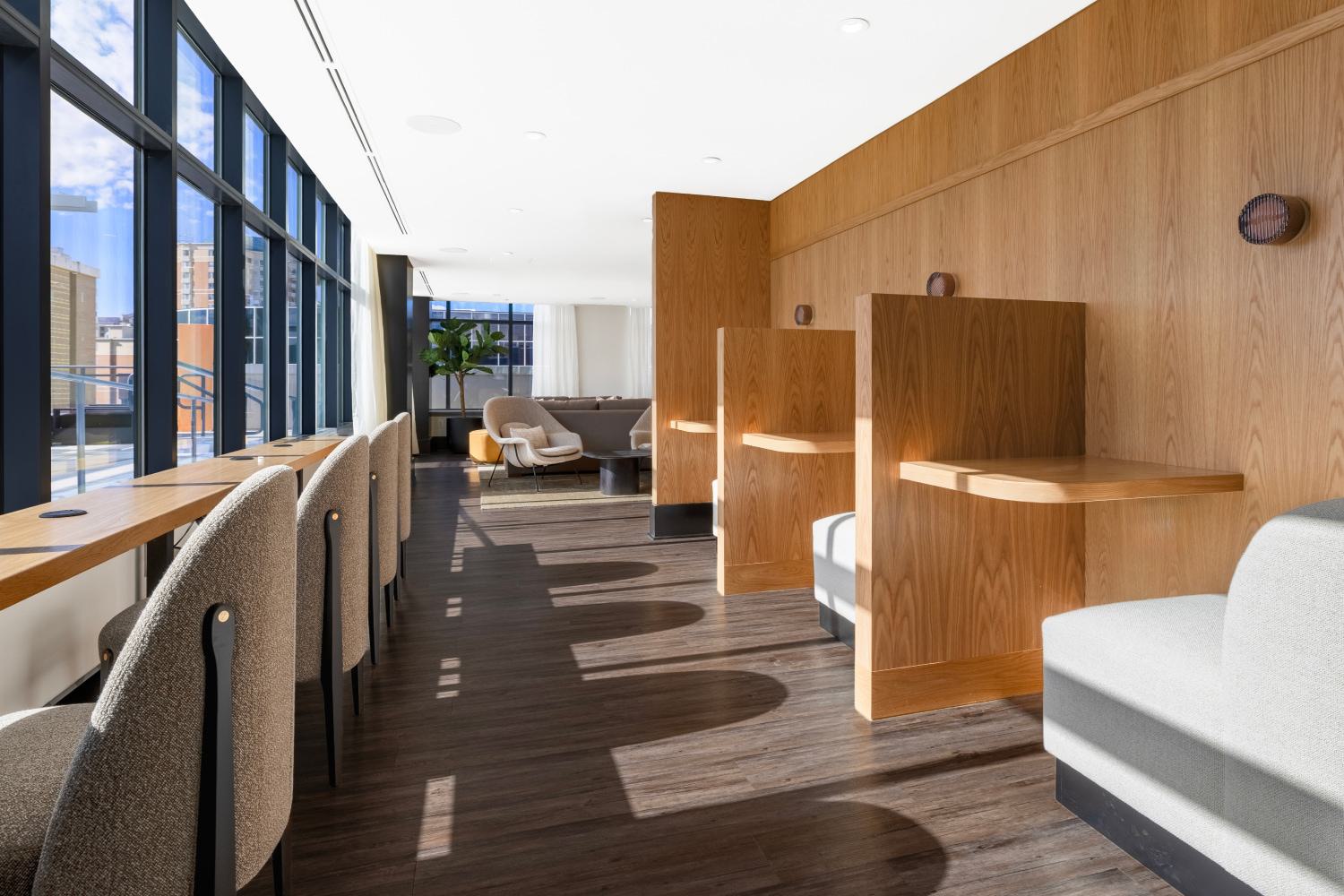 Modern coworking space at Latitude Apartments in Virginia Square with built-in wood study pods, bar-height work seating, plush lounge areas, and large windows bringing in natural light.