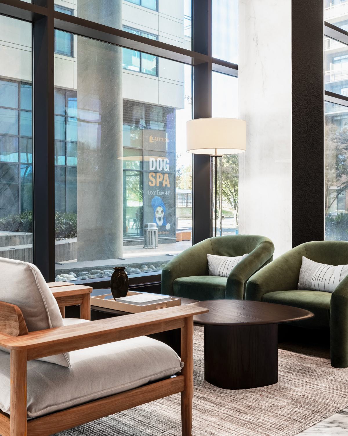 Modern lounge seating area at Latitude Apartments in Virginia Square with green accent chairs, wood furnishings, and natural light from expansive windows.