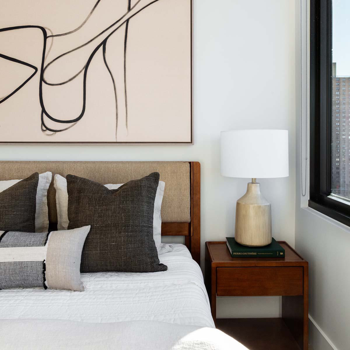 Light-filled living room at Latitude Apartments in Virginia Square with oversized windows, wood-style flooring, modern sectional seating, and green treetop views.