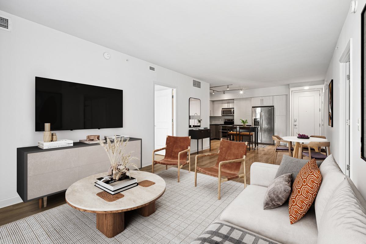 Bright, open-concept apartment interior at Latitude Apartments in Arlington, VA, featuring a modern kitchen with stone waterfall island, stainless steel appliances, contemporary cabinetry, and a living area with large windows and curated furnishings.