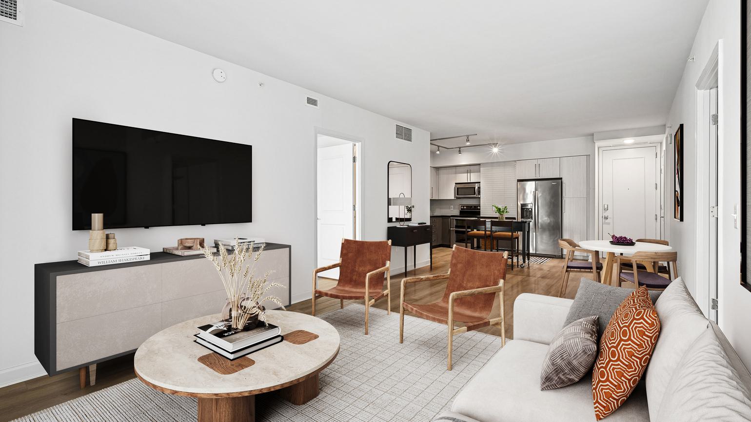 Bright, open-concept apartment interior at Latitude Apartments in Arlington, VA, featuring a modern kitchen with stone waterfall island, stainless steel appliances, contemporary cabinetry, and a living area with large windows and curated furnishings.
