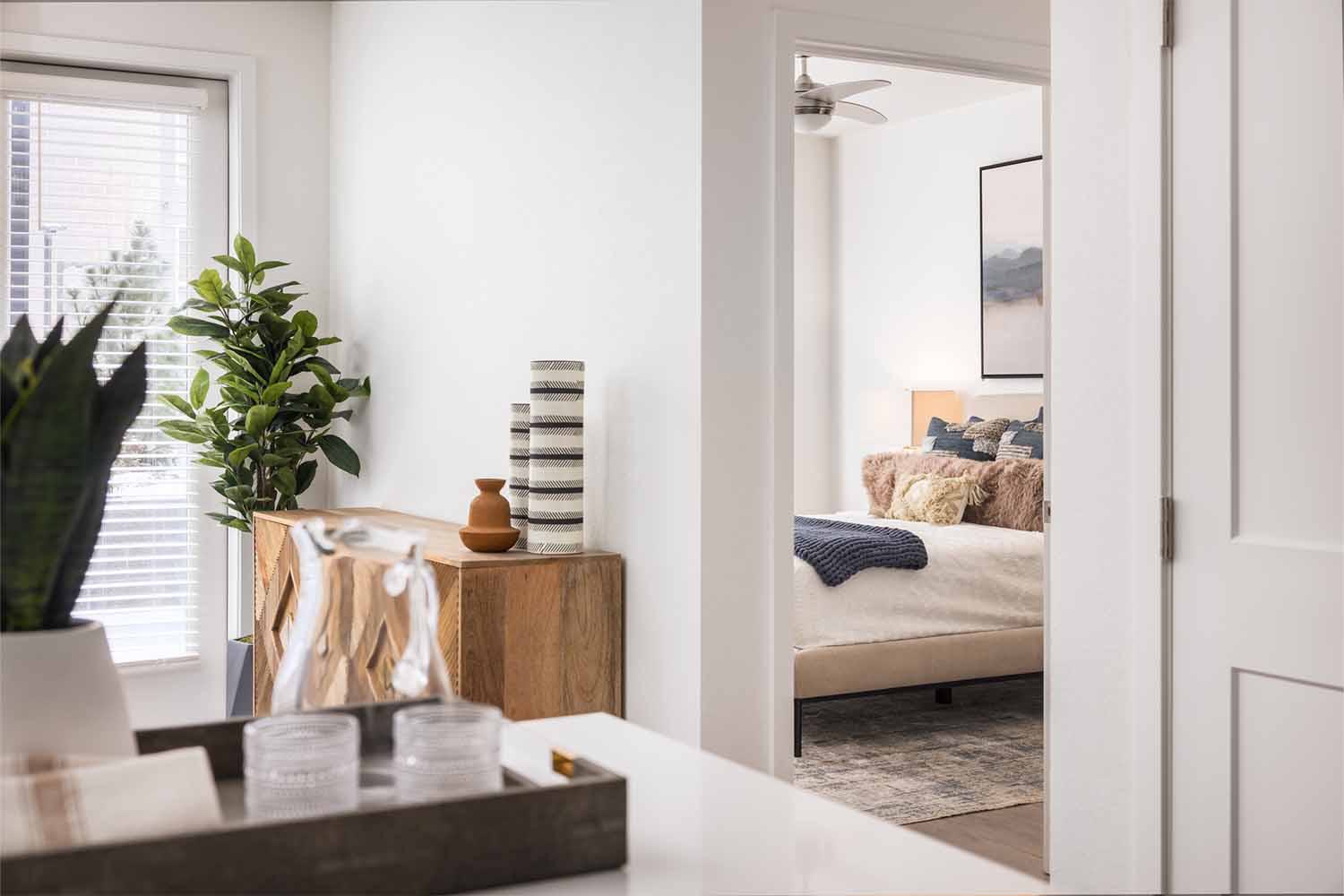 Close-up of a modern apartment kitchen island at Latitude Apartments in Arlington, VA, featuring a polished chrome gooseneck faucet set into a smooth stone countertop, with stainless steel refrigerator and minimalist cabinetry in the background.