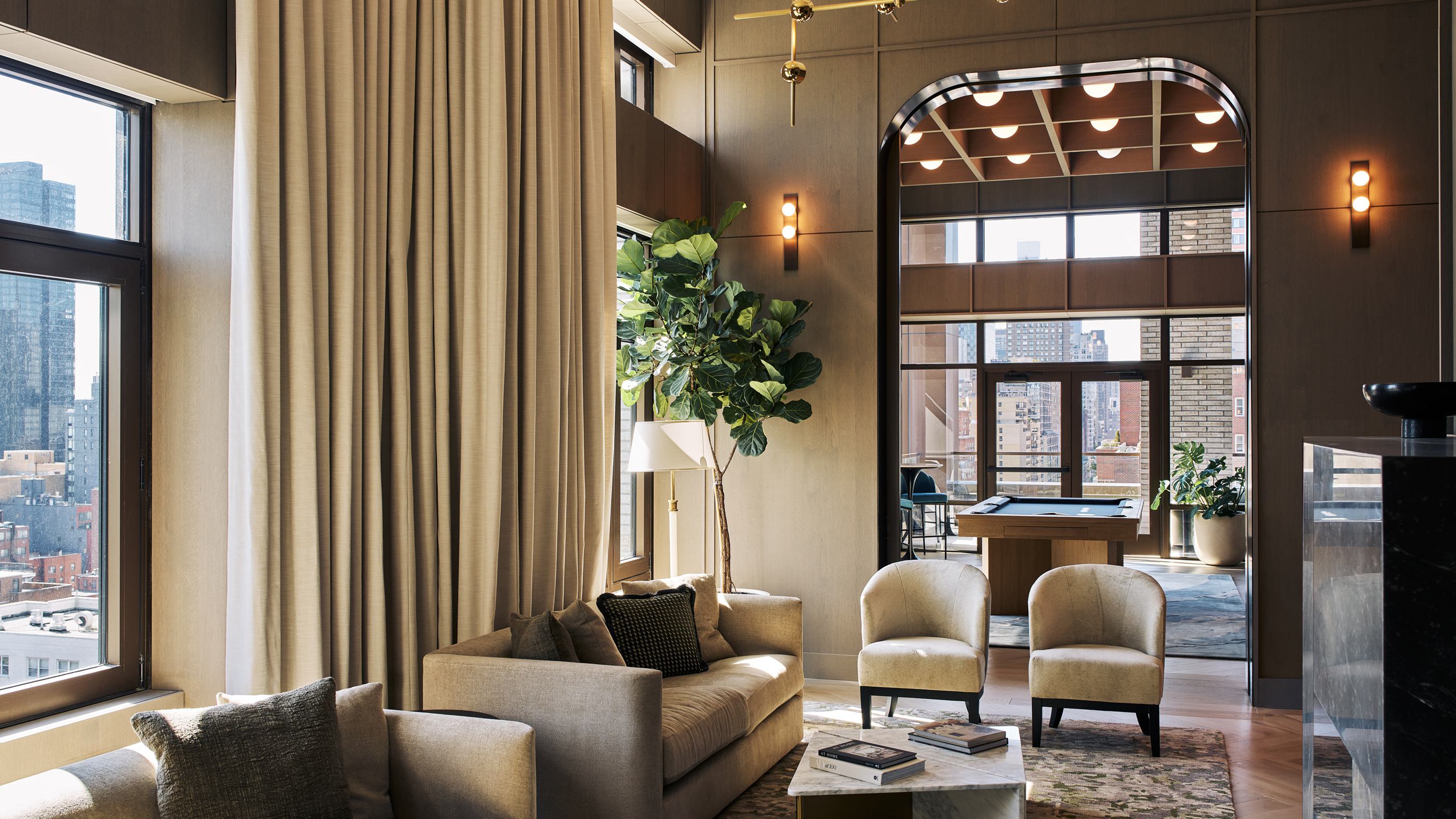 stylish game room with a wooden pool table, high ceilings, and floor-to-ceiling windows that offer a city view, complemented by warm wood paneling, elegant wall sconces, and cozy bar seating.
