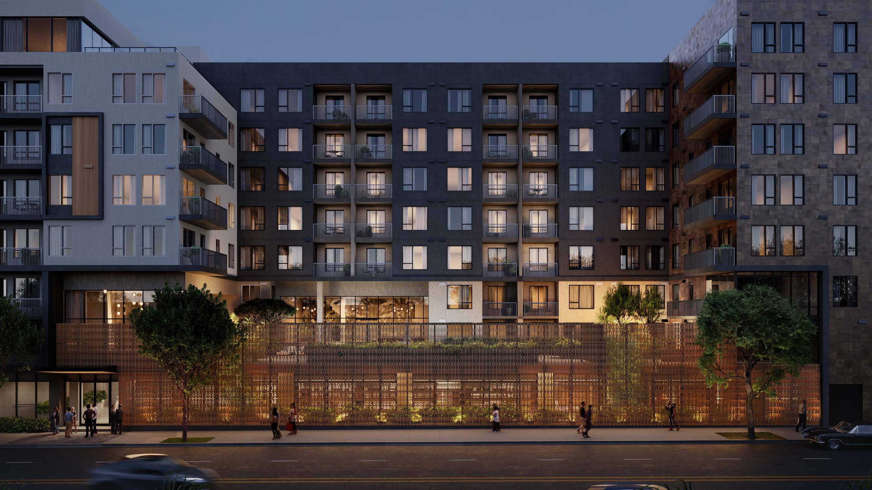 Rowyn multi-story apartment building at dusk, featuring warm interior lighting, private balconies, and a stylish ground-level facade with intricate metalwork and lush greenery.