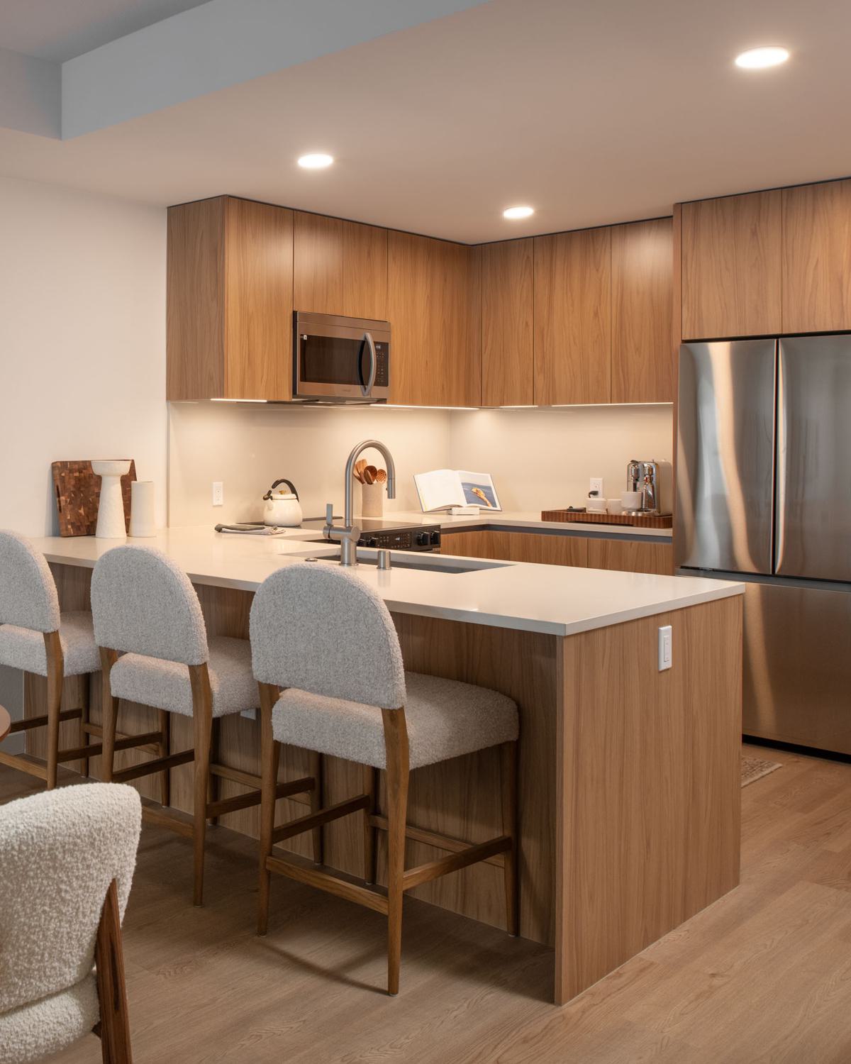 stylish resident lounge with warm earthy tones, plush seating, terracotta pendant lighting, and large windows that bring in natural light and greenery.
