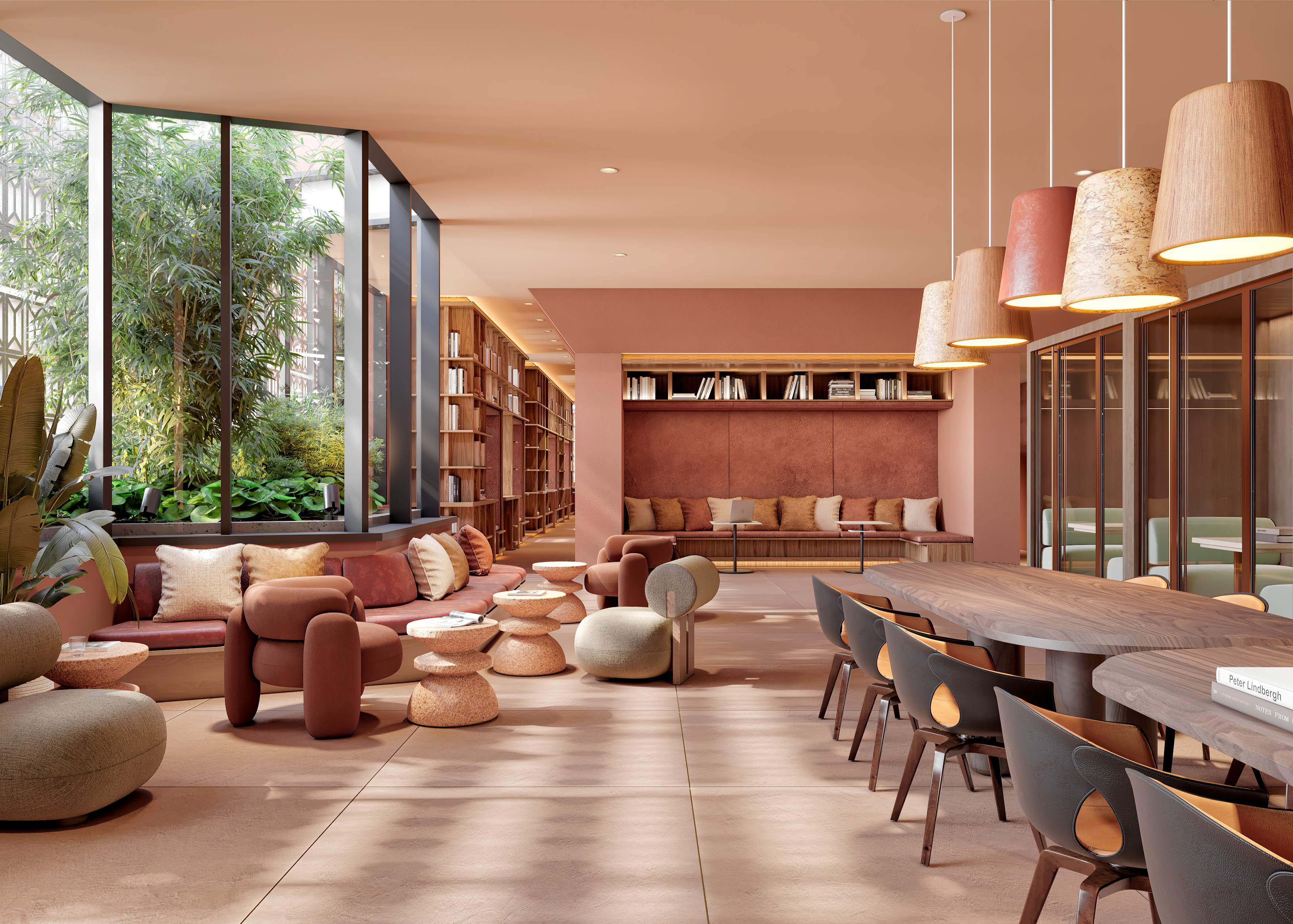 A warm, terracotta-toned lounge at Rowyn in Hillcrest, San Diego, featuring plush curved seating, soft pillows, and tiered stone tables beside a large window framing lush greenery. Built-in bookshelves line the walls, and a long wooden table with sculpted chairs and pendant lights creates a sophisticated co-working and gathering space.