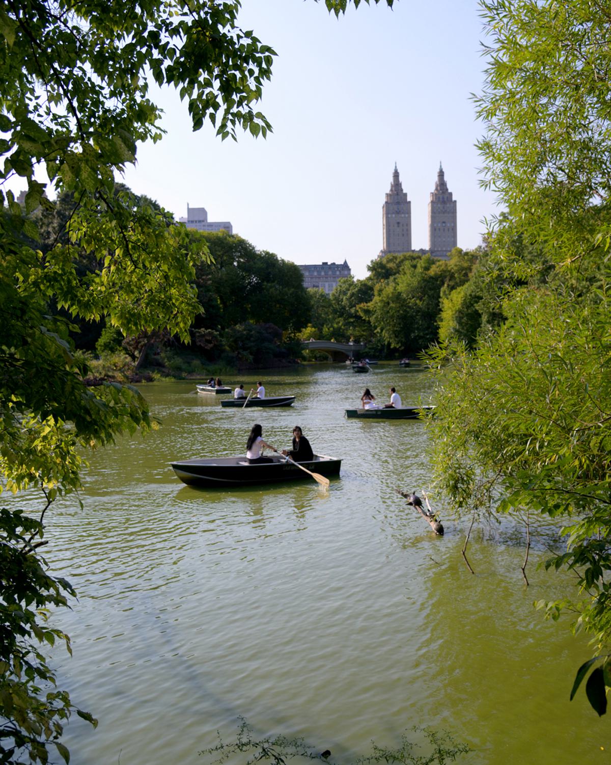 two boaters enjoying an excursion on the pond in leafy and green central park
