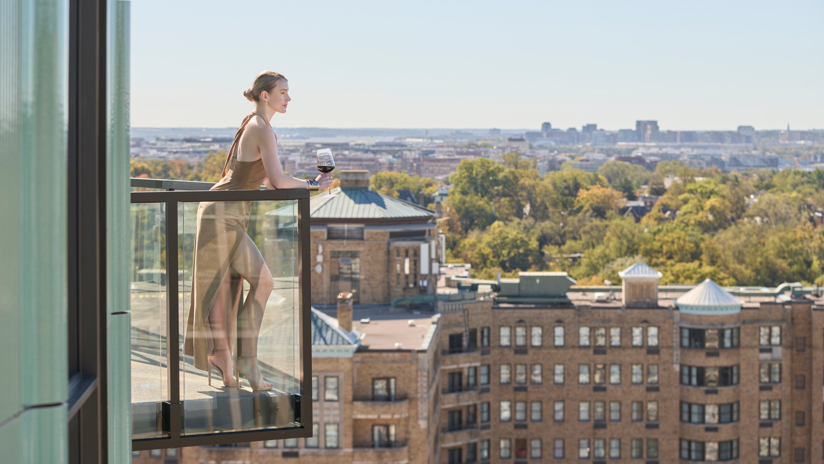 A woman on a balcony with sweeping views of Woodley Park and Washington DC