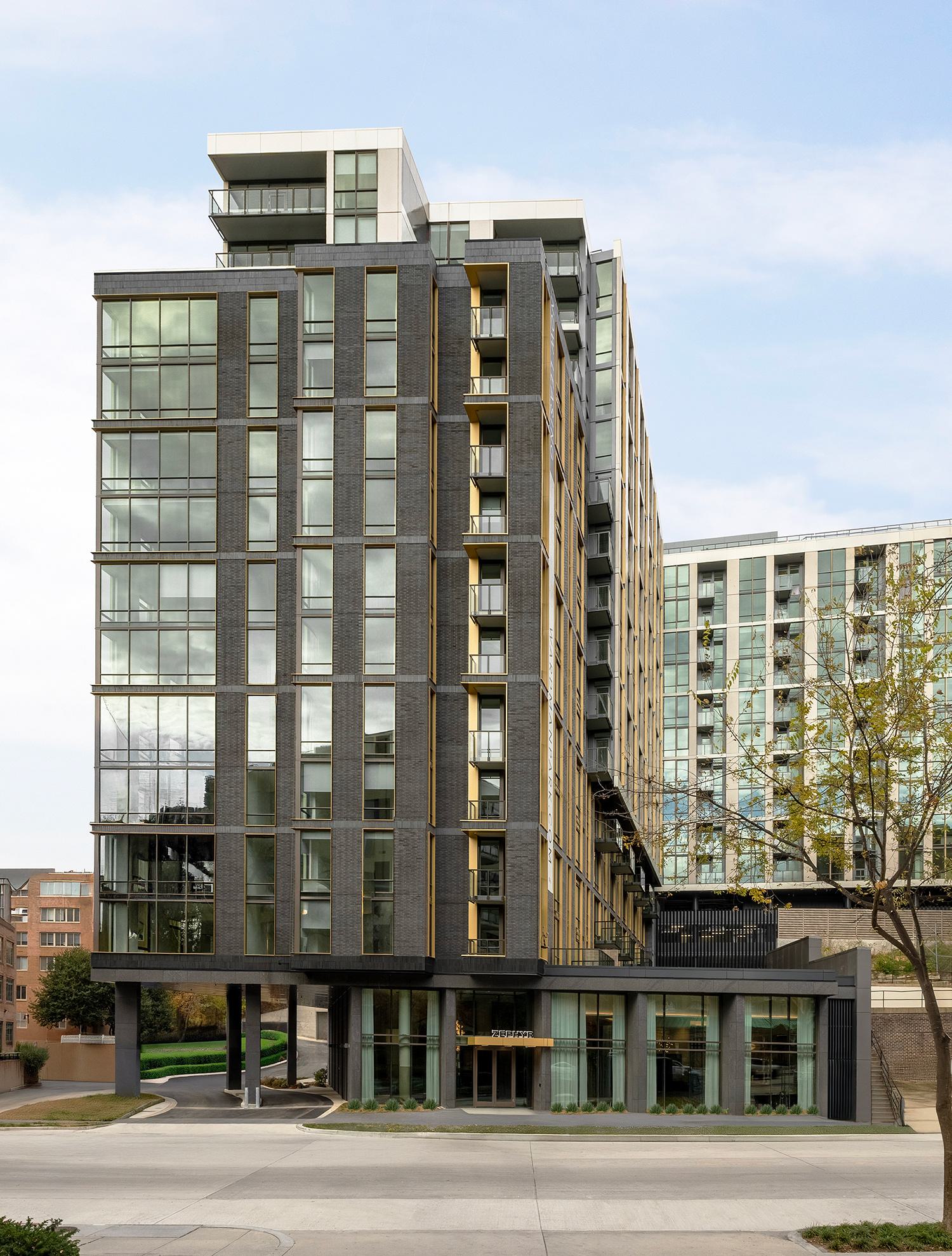 Bedroom at Zephyr in Woodley Park, DC, featuring a soft neutral palette, modern lighting, and floor-to-ceiling windows with views of the Washington National Cathedral rising above the treetops.