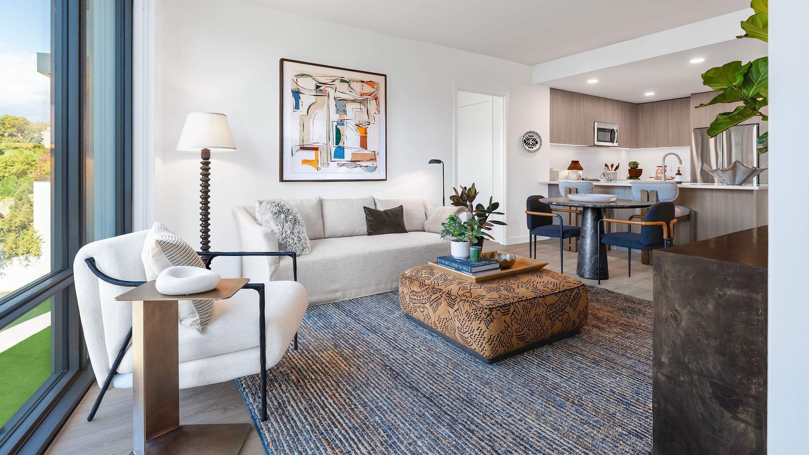 Living room at Zephyr in Woodley Park, DC, featuring a neutral-toned sofa, modern accents, and floor-to-ceiling windows with treetop views of the Washington National Cathedral in the distance.