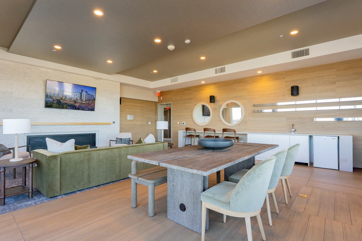 Contemporary clubhouse detail at The Triton Apartments with a wood dining table, colorful chairs, sculptural decor, and a unique divider made of decorative oars.