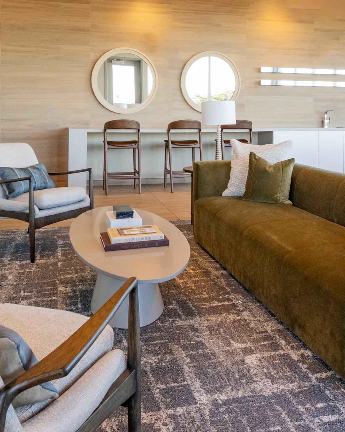 Cozy bedroom with a dark upholstered headboard, layered neutral pillows, and a bedside table styled with flowers, a book, coffee, and a pastry, creating a warm and inviting atmosphere.