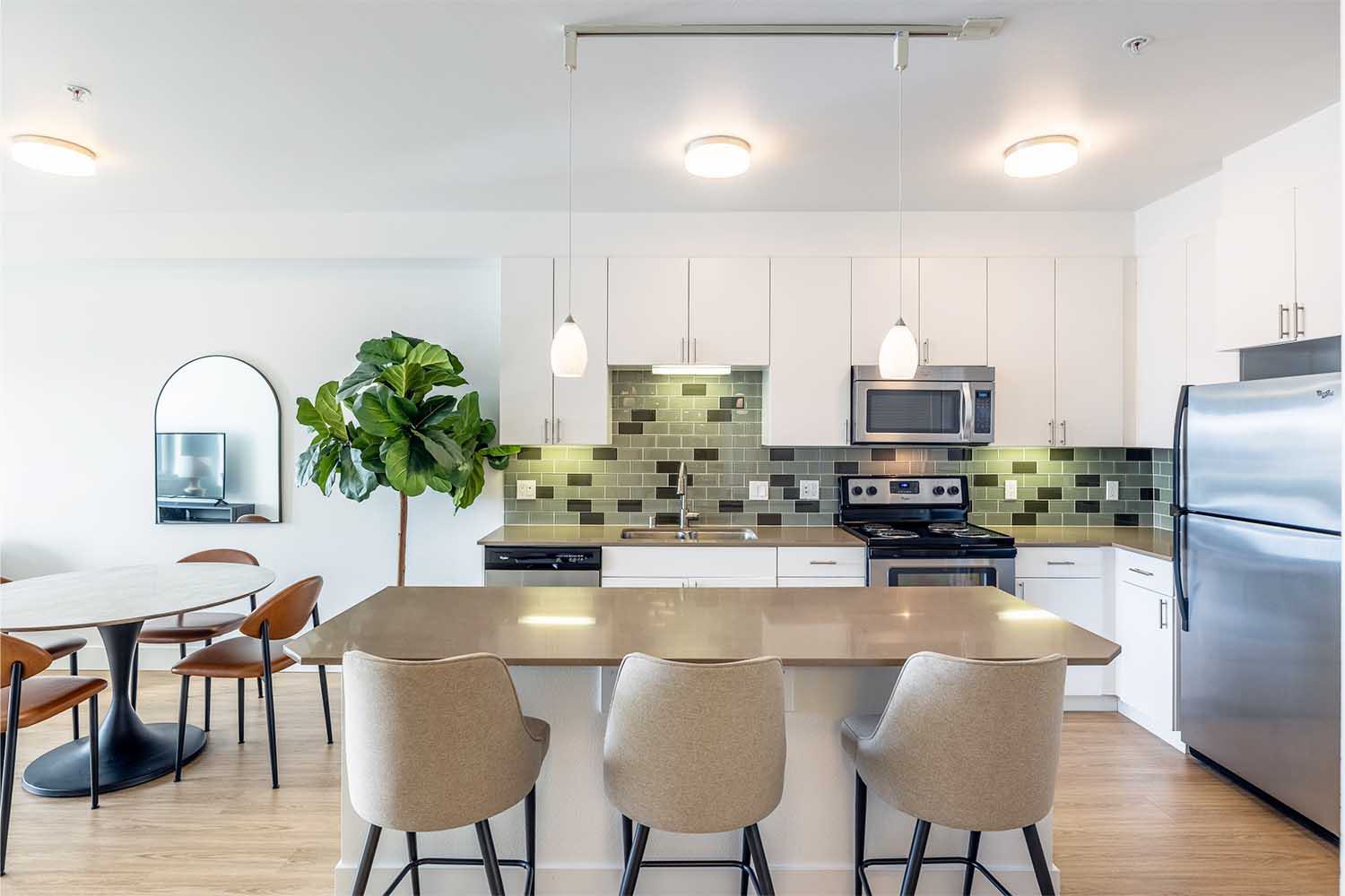 Cozy bedroom with neutral plaid bedding, a potted plant, and a large window offering natural light and views of a green hillside in Ballard in the distance.