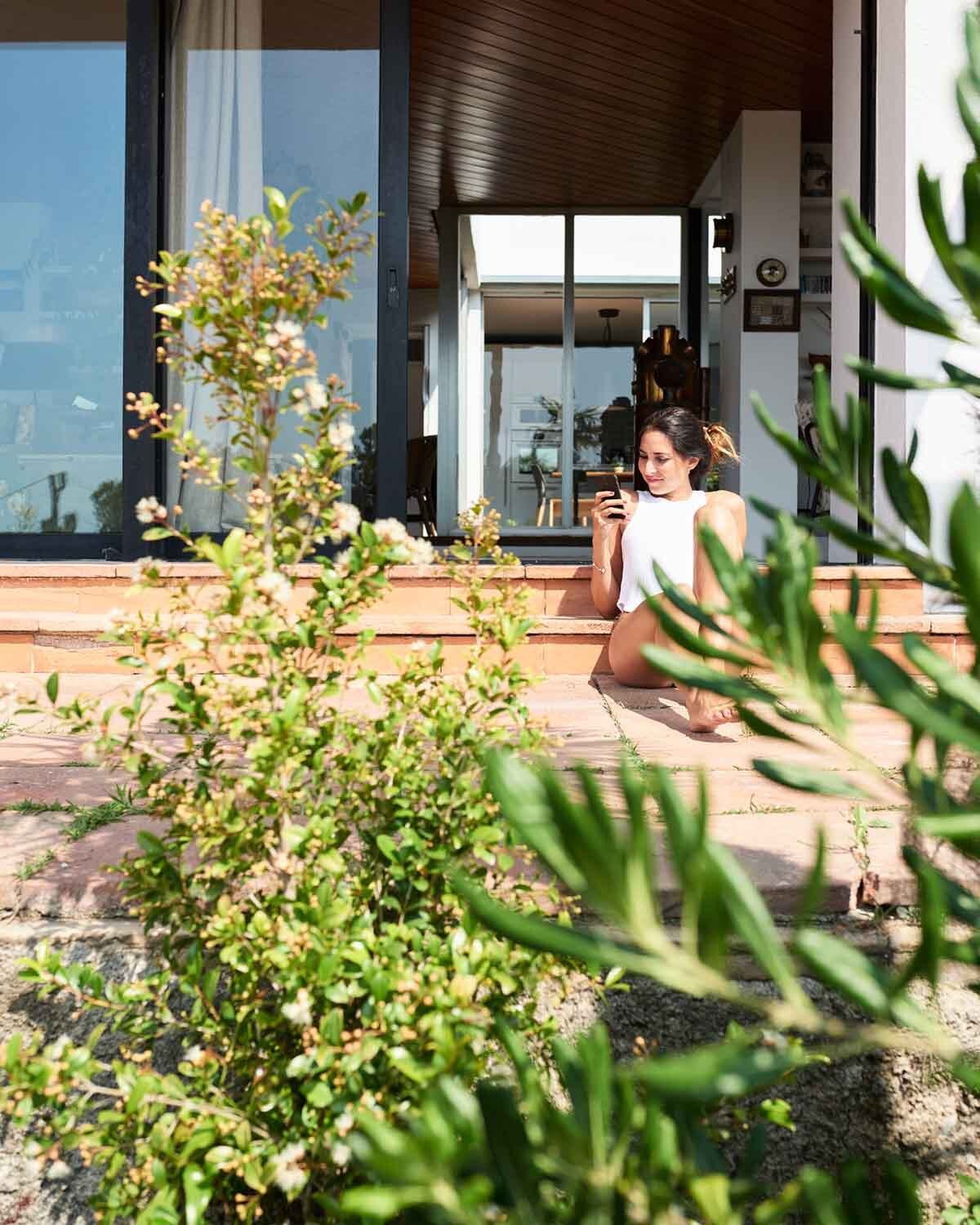 Contemporary kitchen with sleek white cabinetry, a dark tile backsplash, and a cozy dining island with wooden bar stools and warm wood flooring.