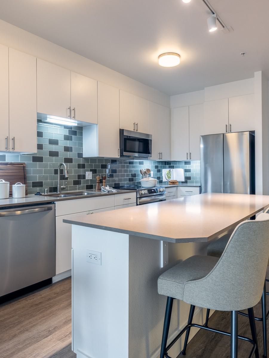 Modern apartment living room with neutral-toned furniture, large windows, and a private balcony.