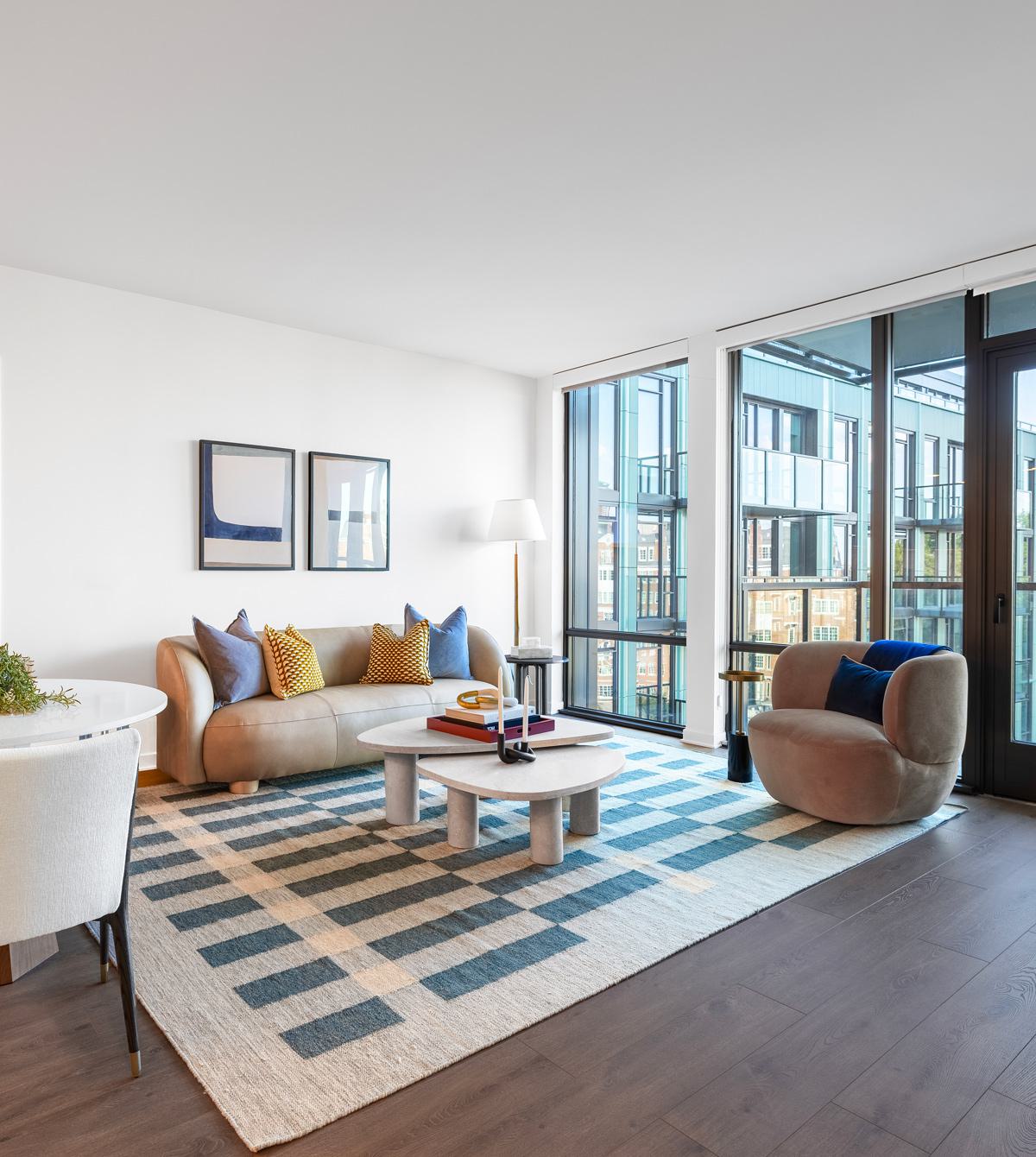 elegant open-concept living space with a modern kitchen, cozy seating area, and a wood dining table set beside floor-to-ceiling windows.