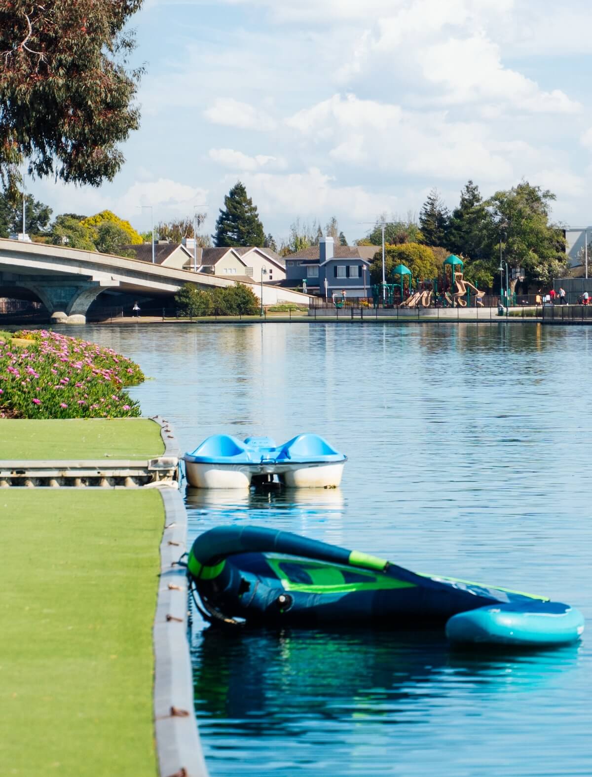 Private dock on the Foster City lagoon beside The Triton Apartments, featuring a boat with a red canopy tied along the waterfront under a clear blue sky.
