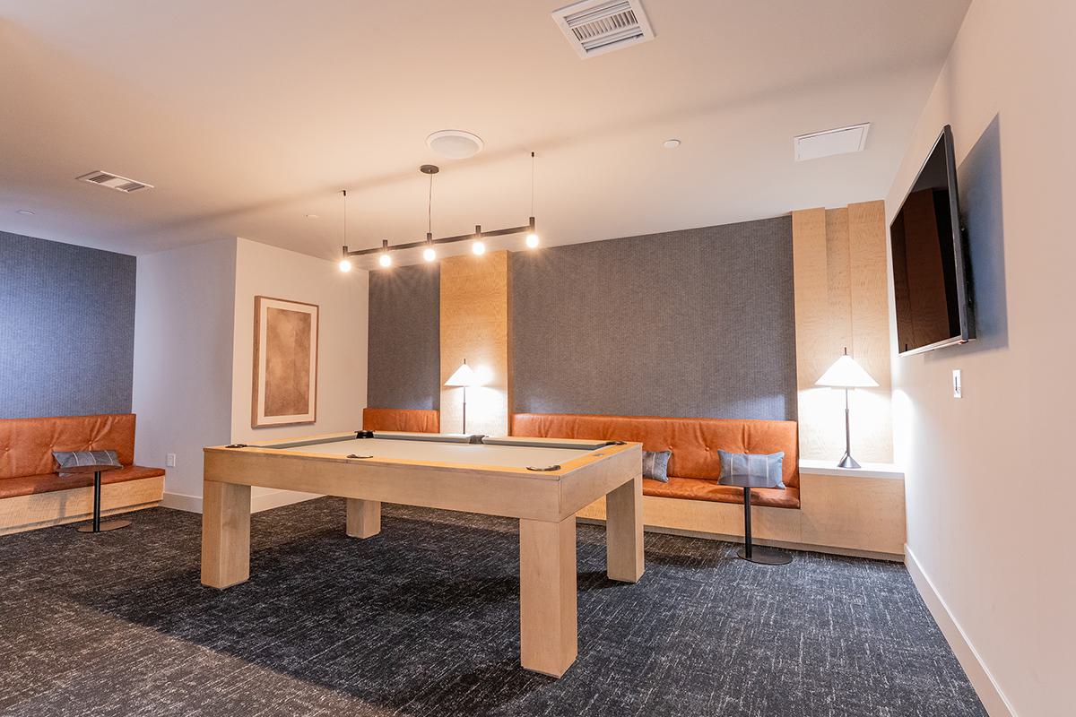 Modern community clubhouse at The Triton Apartments featuring a spacious lounge with contemporary seating, workstations, large windows for natural light, and stylish decor.