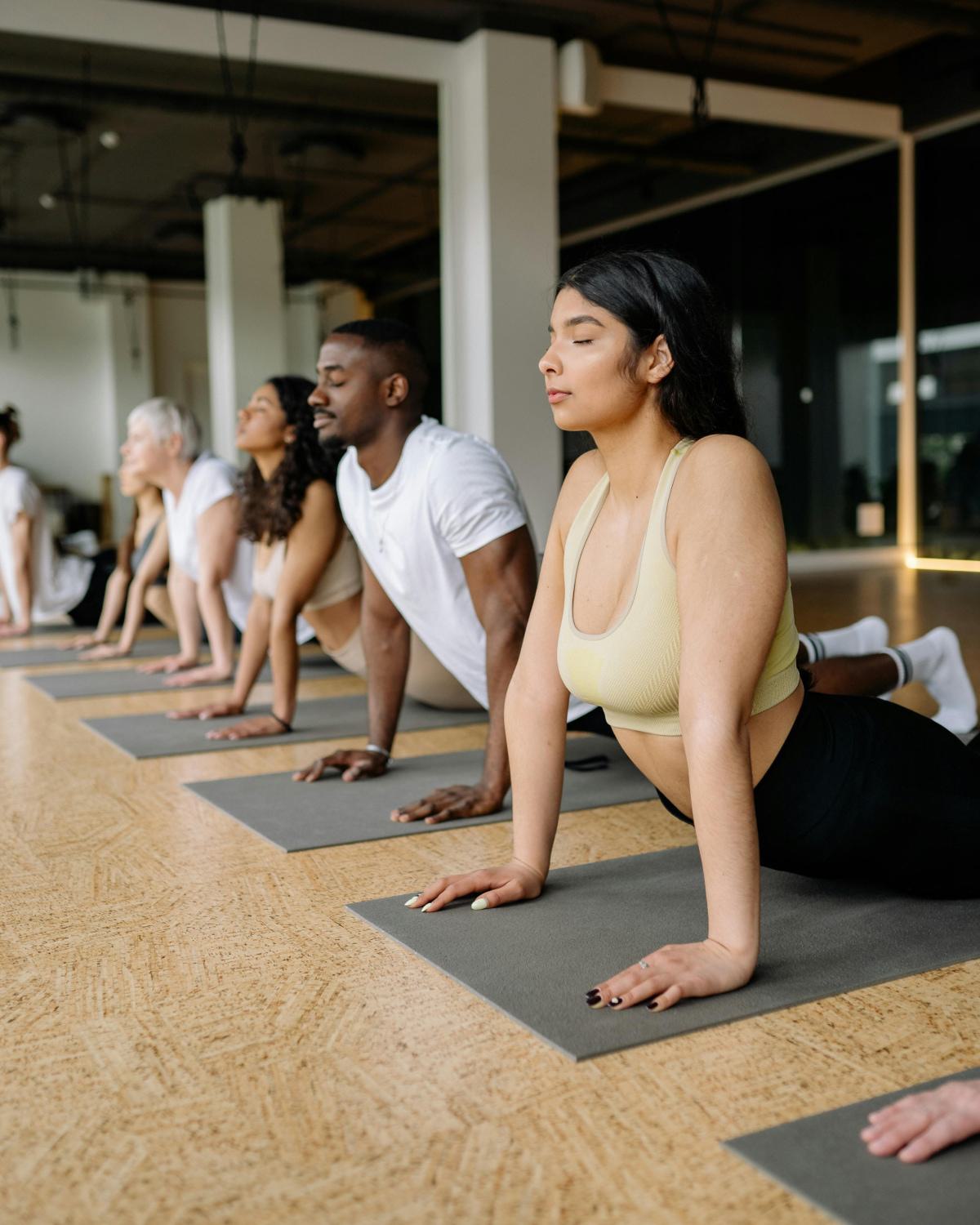 A group of people holding a pose during a yoga class, representing the yoga studio at Alchemy.