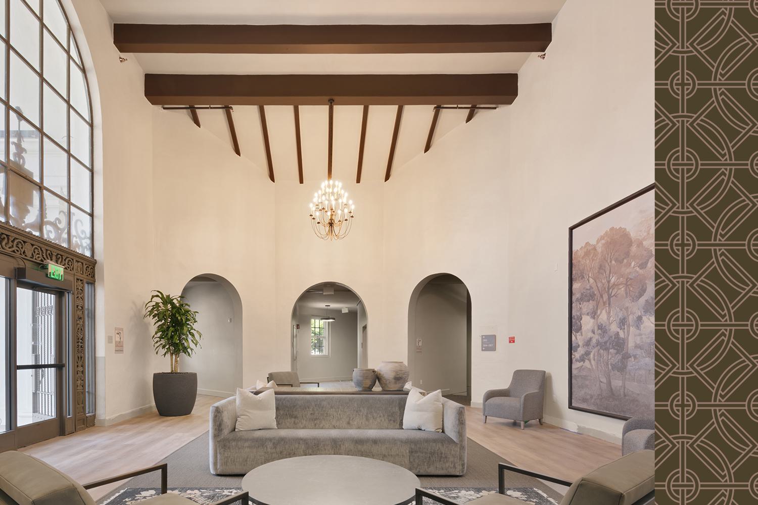 This bright, inviting lounge features clean white tables and chairs, a long orange banquette, and warm wood slat ceilings and columns. Natural light floods the space through large windows, creating a modern yet welcoming atmosphere ideal for casual gatherings or work sessions.