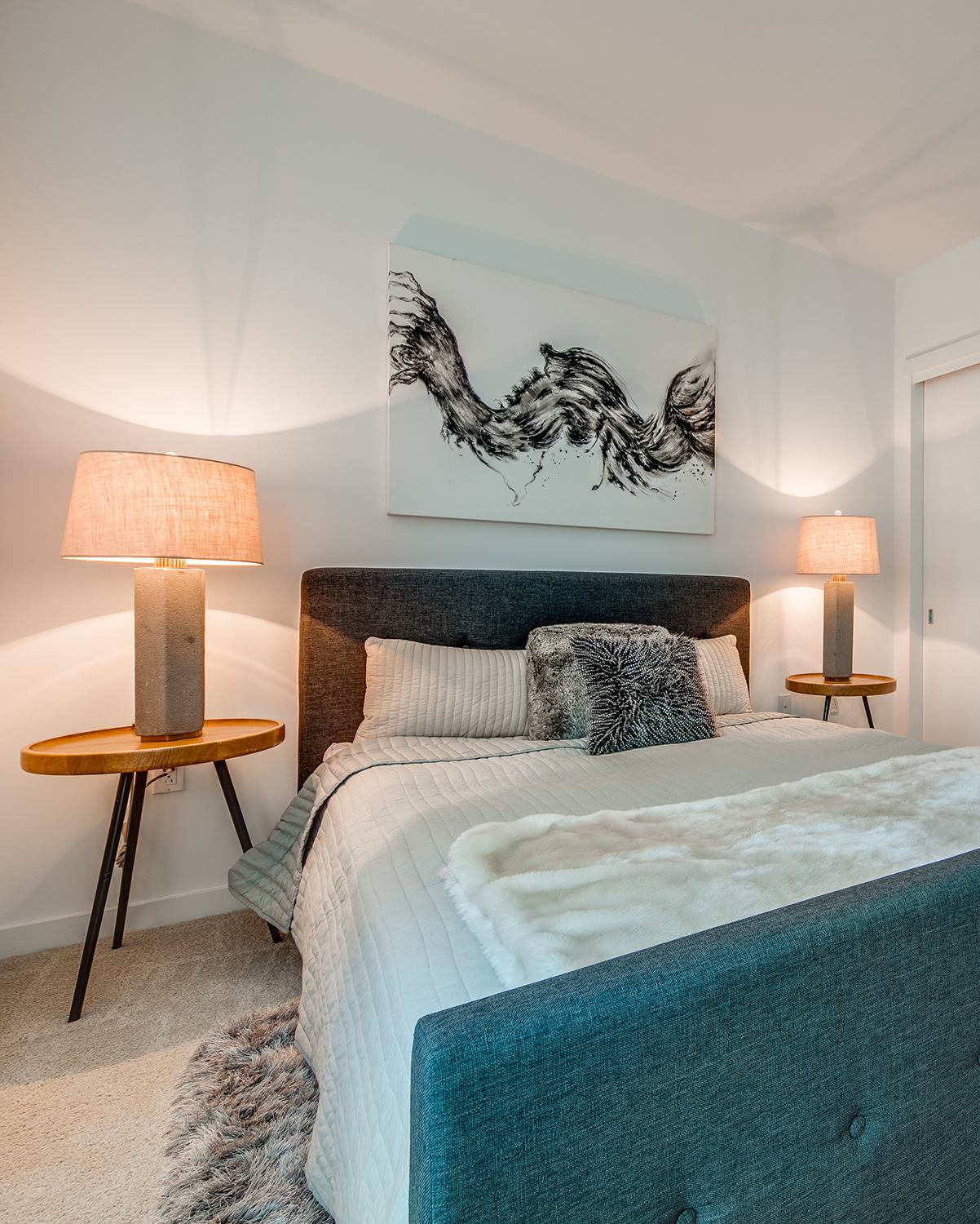 Bright, modern living room  with large window features a soft gray sofa with mustard yellow accent pillows, set against a cheerful yellow accent wall. Concrete cube tables, a dark woven rug, and minimalist decor add a clean, contemporary touch.