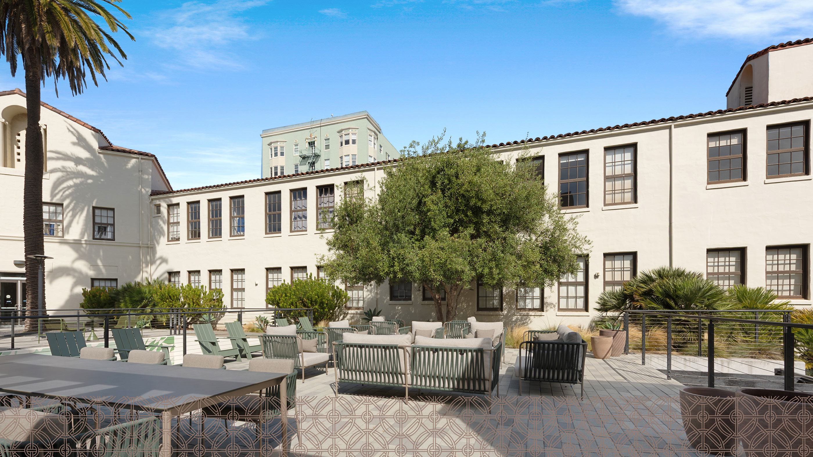 Alchemy contemporary apartment building in Hayes Valley with clean lines, large windows, and private balconies, framed by sleek siding and light neutral tones. Trees line the paved courtyard below, giving the space a modern, walkable neighborhood feel.