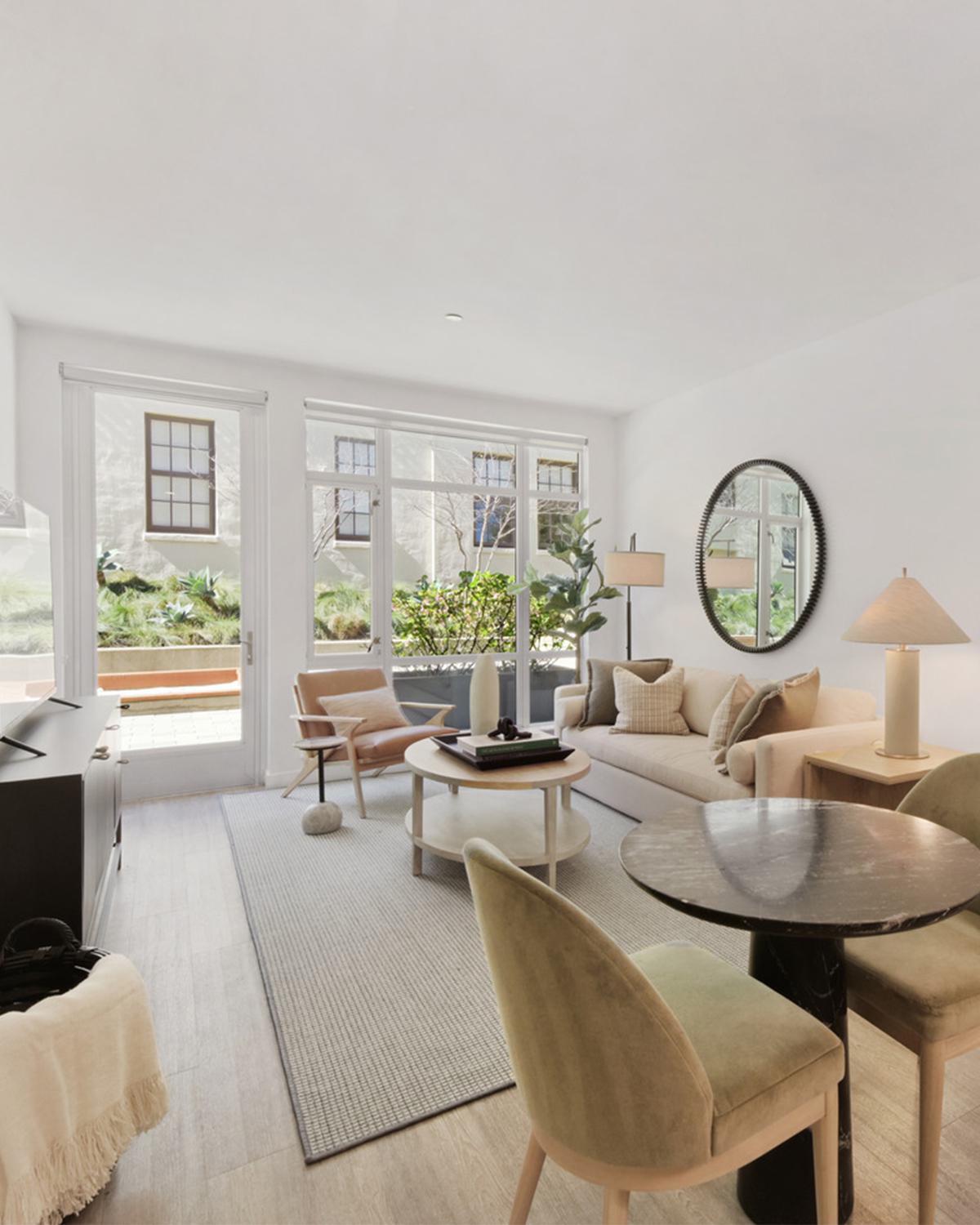 Bright, modern open layout of apartment with tall windows overlooking courtyard.