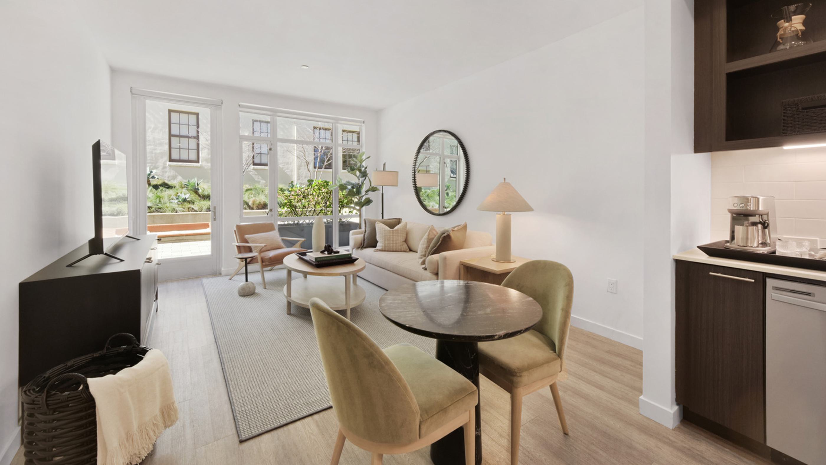 Bright, modern open layout of apartment with tall windows overlooking courtyard.