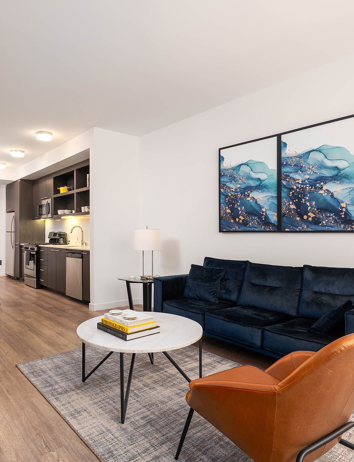 Cozy modern living room with a light gray sectional sofa, yellow accent wall, minimalist decor, wood writing desk, indoor plant, and soft natural lighting.