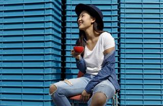 Woman sipping espresso in front of a blue wall
