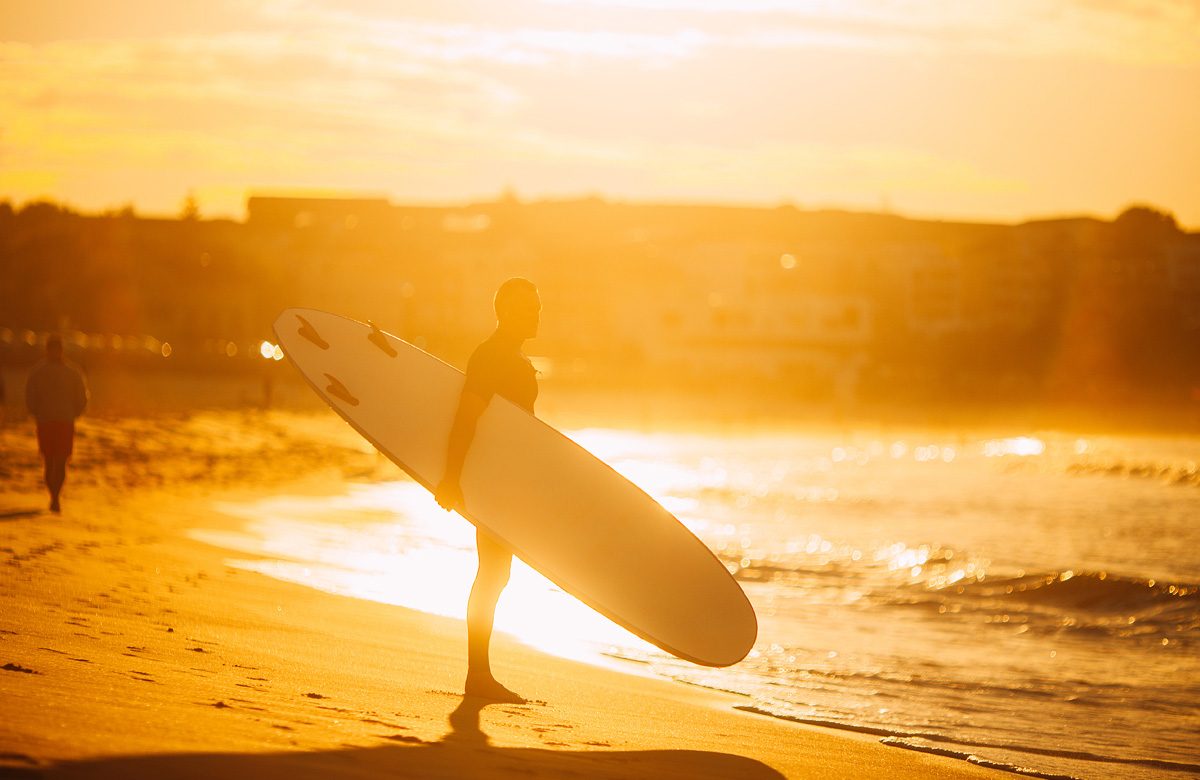 man with surfboard on the beach in sunlight - The Madrid Location - Westchester LA