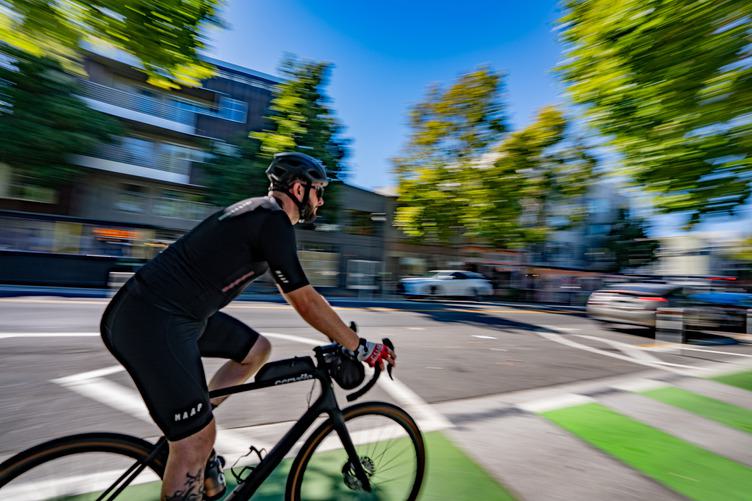 Cyclist riding along the Wiggle bike path in San Francisco’s Lower Haight, using the green-marked lane through a tree-lined residential street.