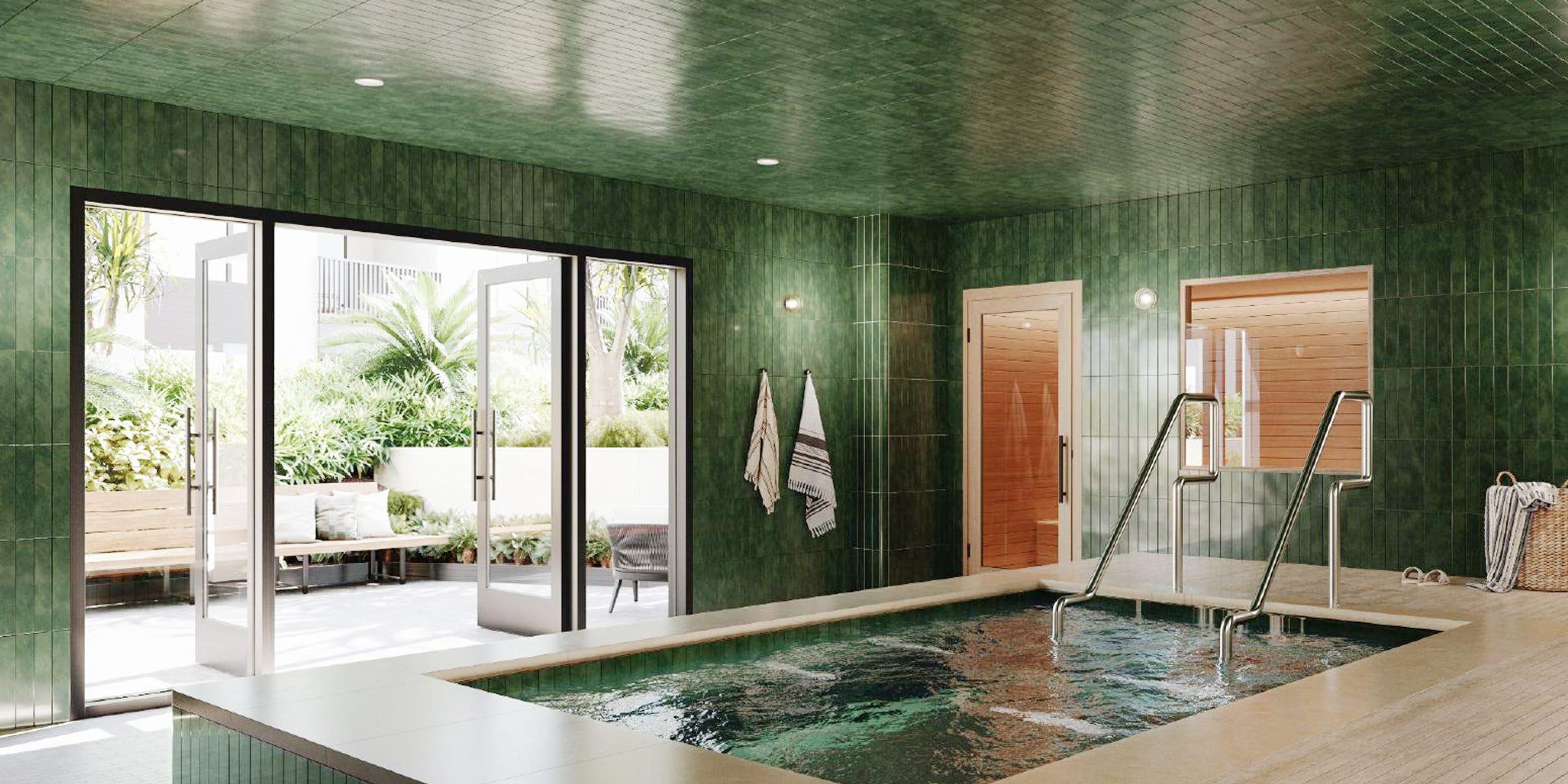 A serene indoor spa features a rectangular soaking pool framed by rich green tile walls and wood-accented sauna rooms. Floor-to-ceiling glass doors open to a tranquil outdoor lounge with blooming trees, cushioned benches, and lush landscaping.