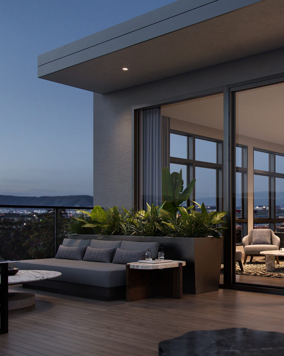 An elevated rooftop terrace at dusk offers stylish outdoor seating with leafy planters and views of the Burlingame cityscape, airport runways, and distant hills. Inside, a warmly lit lounge features modern furniture, textured walls, and a sculptural chandelier, blending indoor comfort with scenic outdoor ambiance.