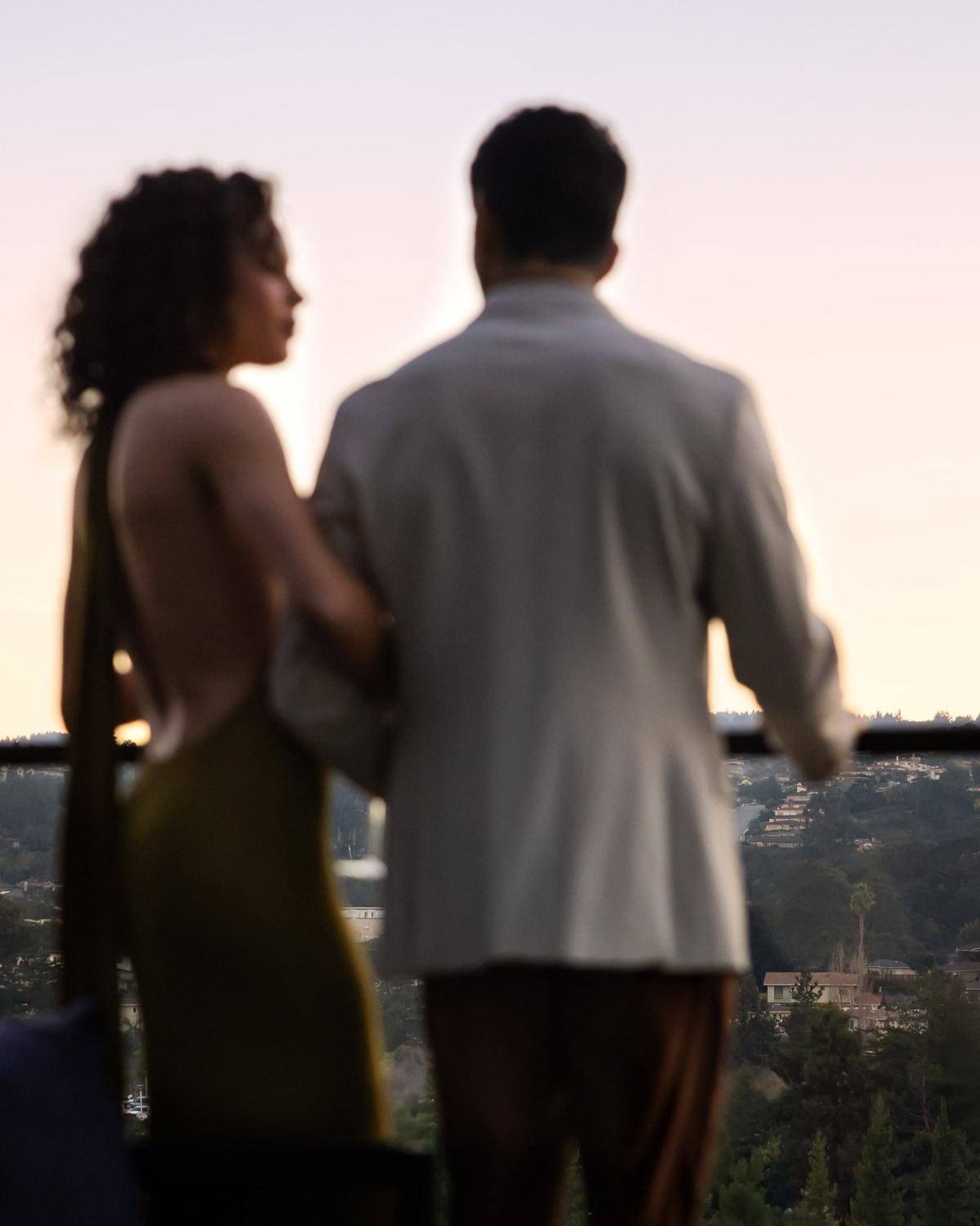 An elevated rooftop terrace at dusk offers views of the Burlingame cityscape and distant hills.