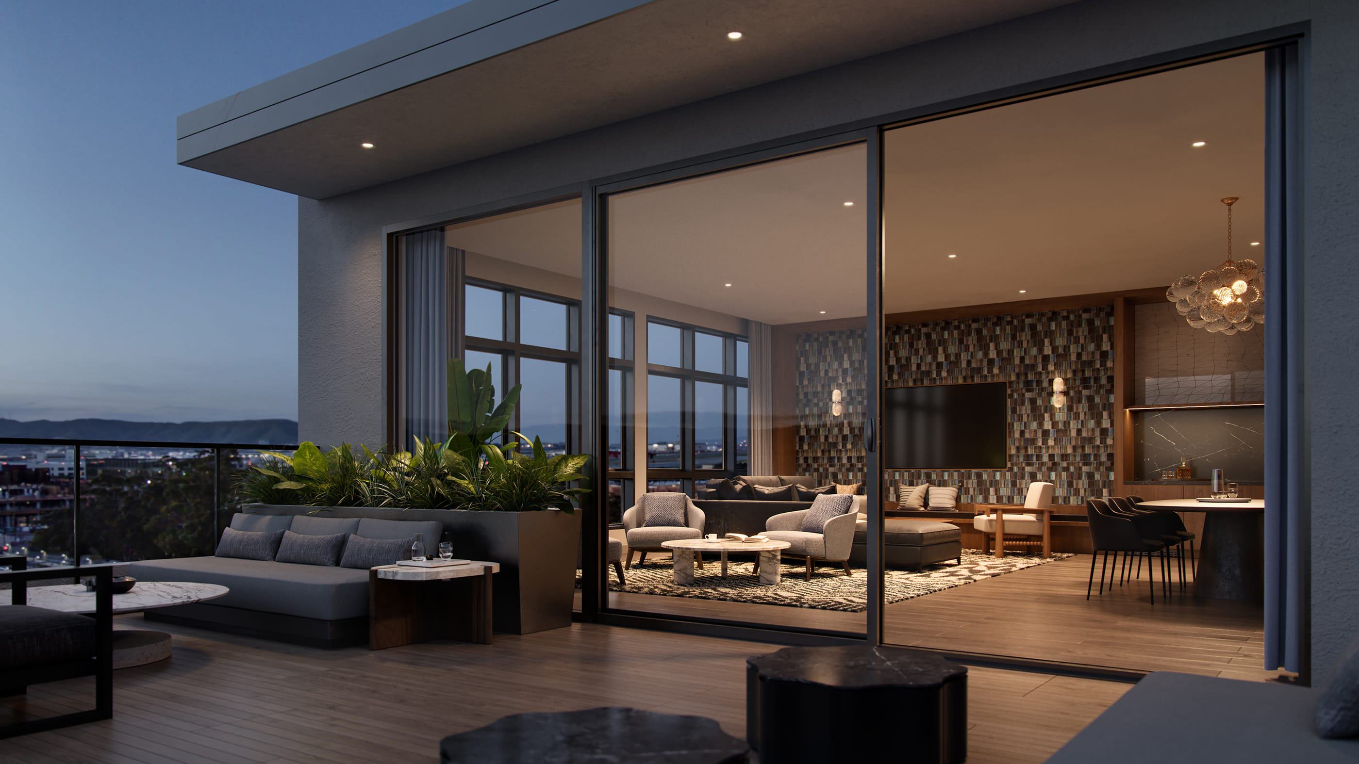 An elevated rooftop terrace at dusk offers stylish outdoor seating with leafy planters and views of the Burlingame cityscape, airport runways, and distant hills. Inside, a warmly lit lounge features modern furniture, textured walls, and a sculptural chandelier, blending indoor comfort with scenic outdoor ambiance.