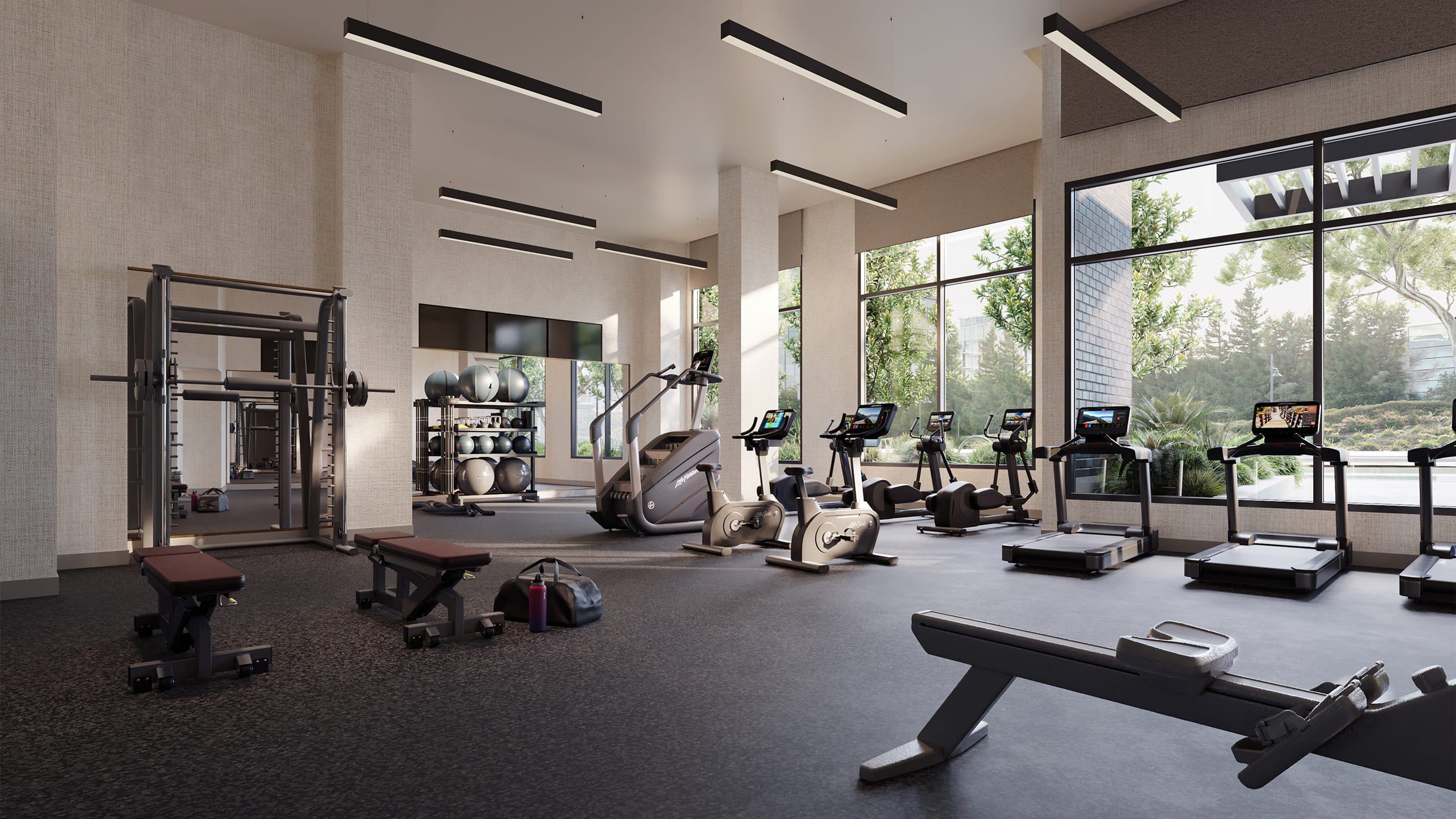A spacious, light-filled fitness center equipped with treadmills, bikes, free weights, and resistance machines. Floor-to-ceiling windows overlook landscaped greenery, creating a calm and energizing workout environment.