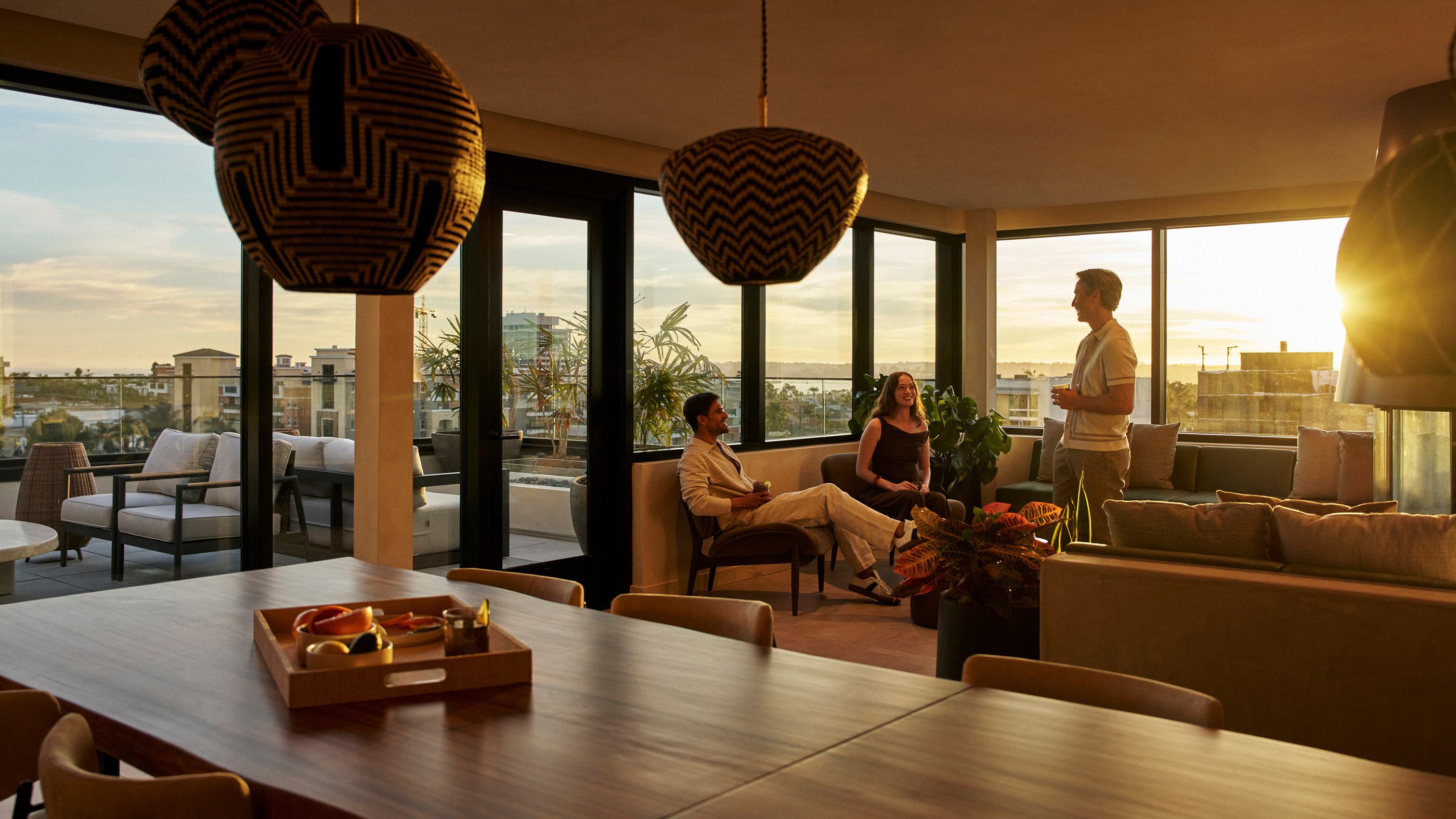 Sophisticated indoor rooftop lounge at Rowyn featuring a modern suspended fireplace, expansive seating, statement lighting, and skyline views of San Diego.
