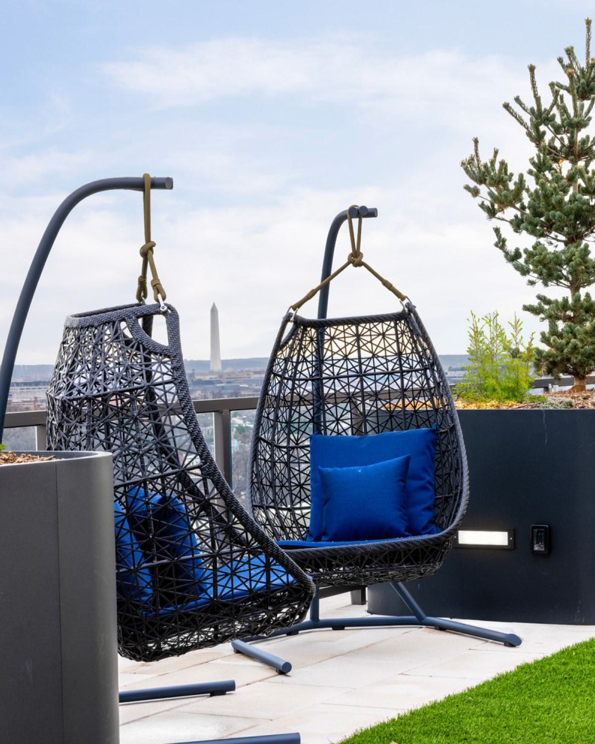 Two hanging chairs on a rooftop with a view.