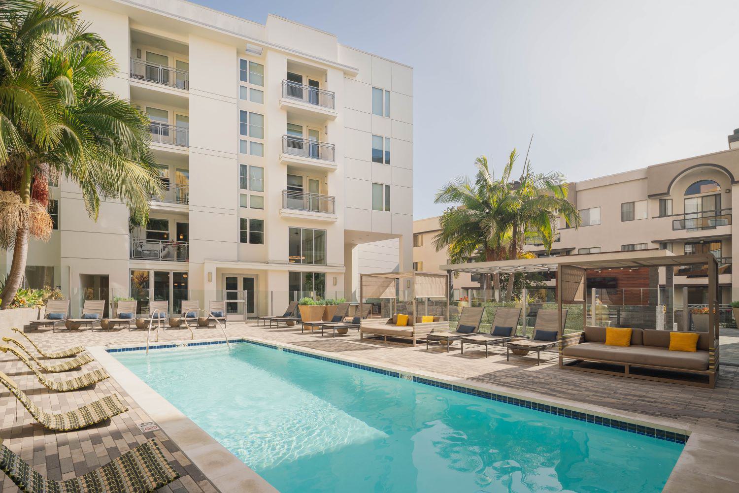 Sophisticated resident apartment building lounge with modern furniture, warm wood tones, and pendant lighting.