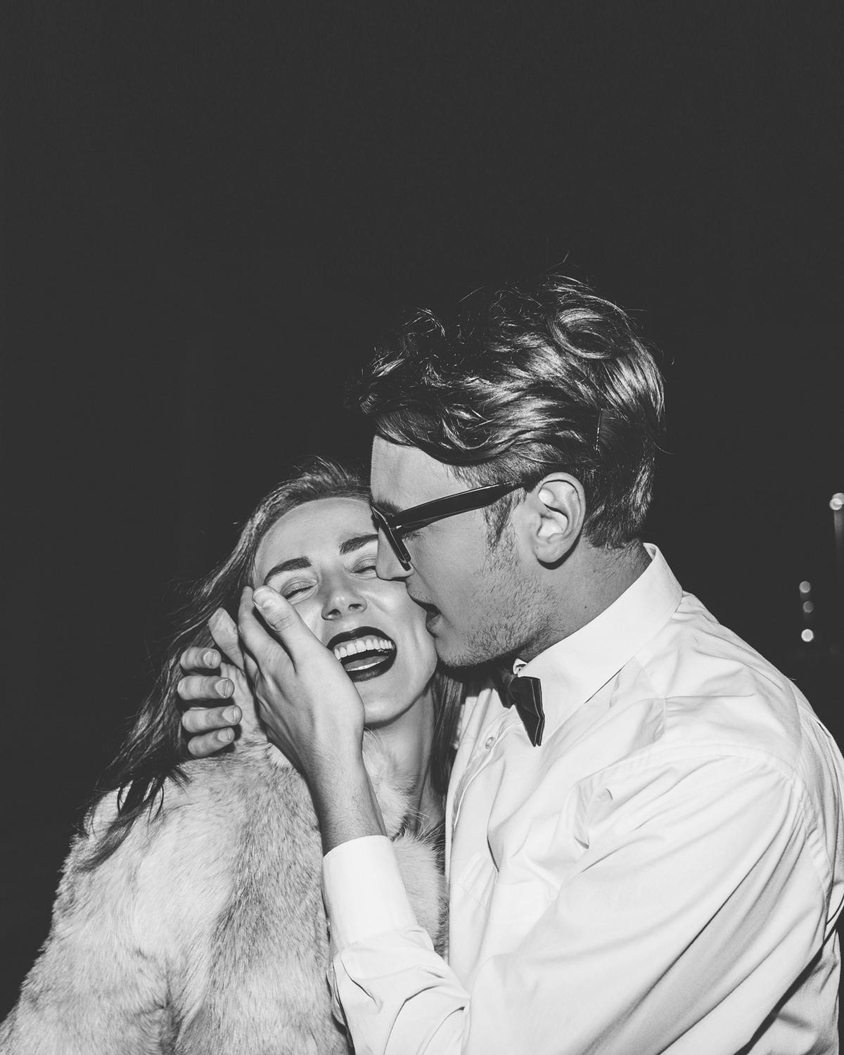 Black-and-white photo of a joyful couple laughing and embracing at night.